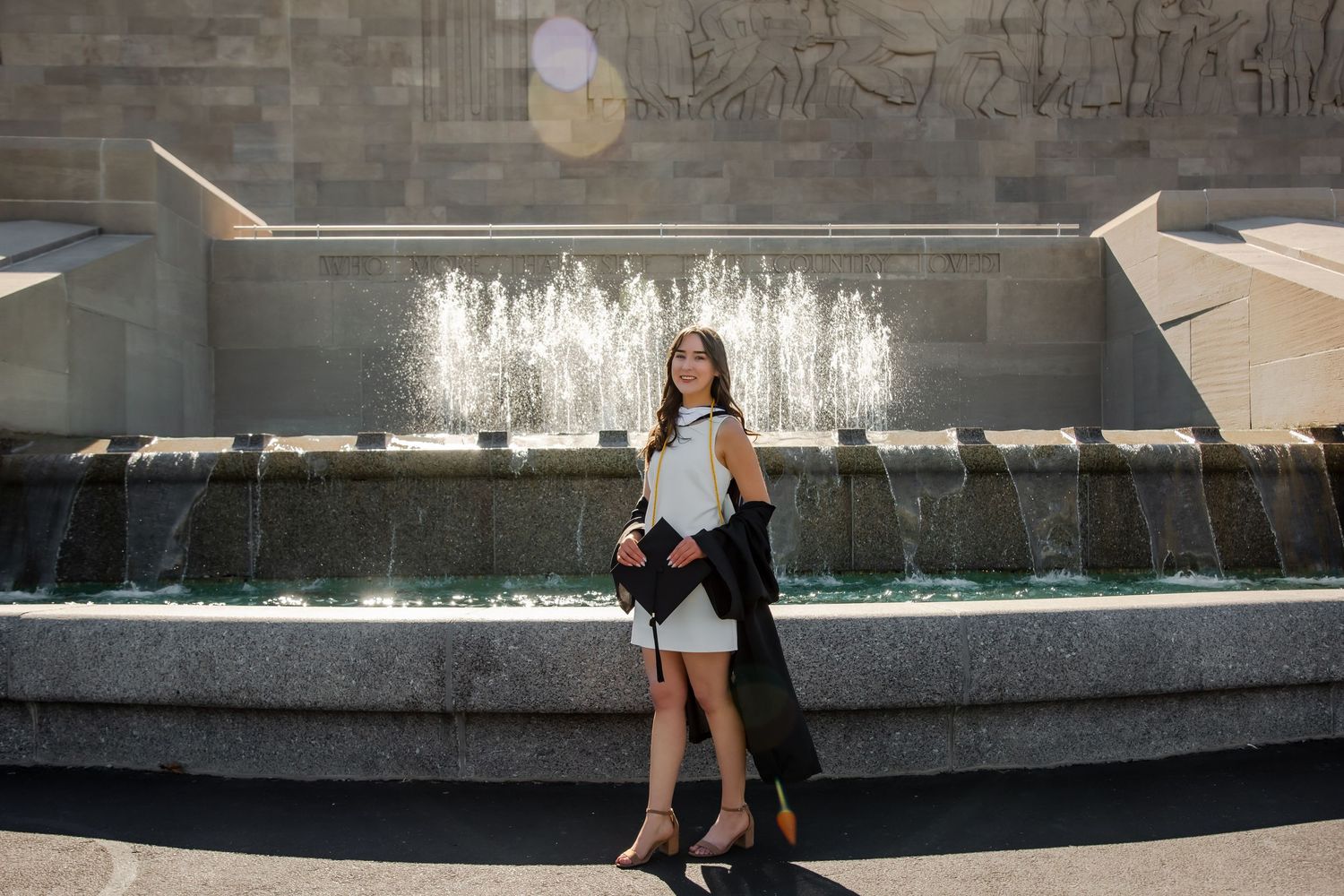 A couple walks along a modern water feature with cascading fountains in an urban plaza setting.