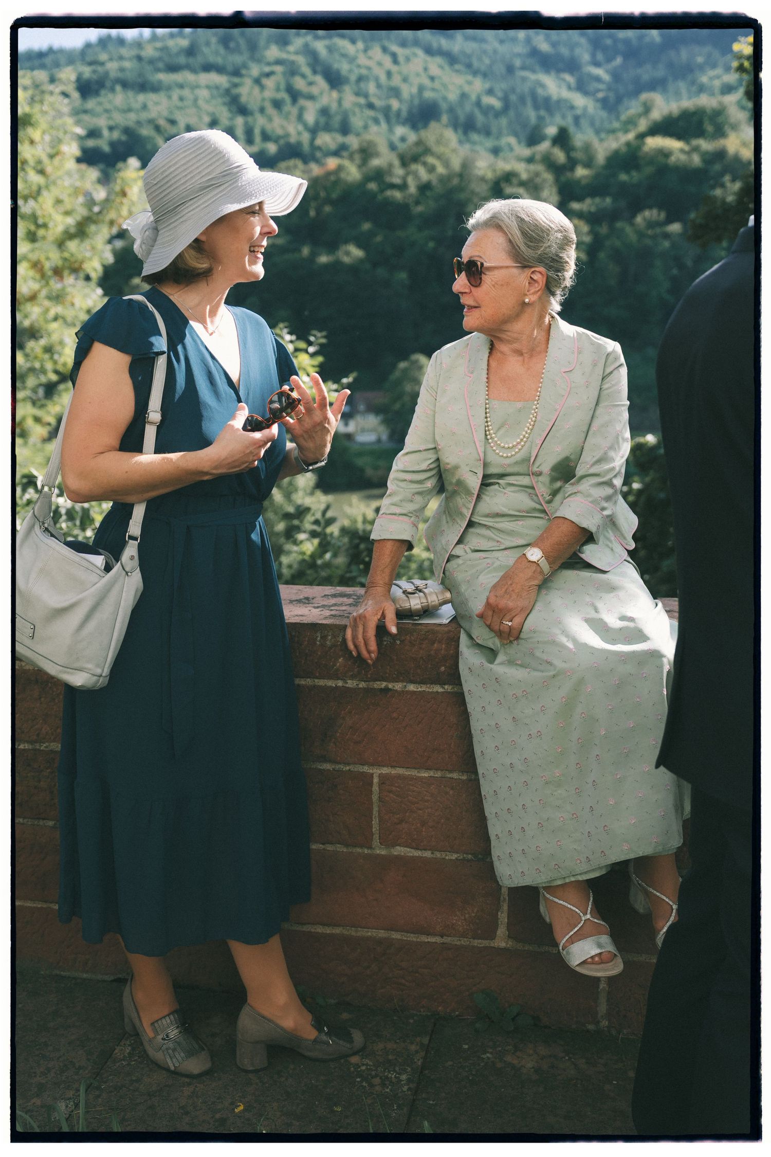 Vintage-style photo of guests in formal attire chatting at an outdoor reception.