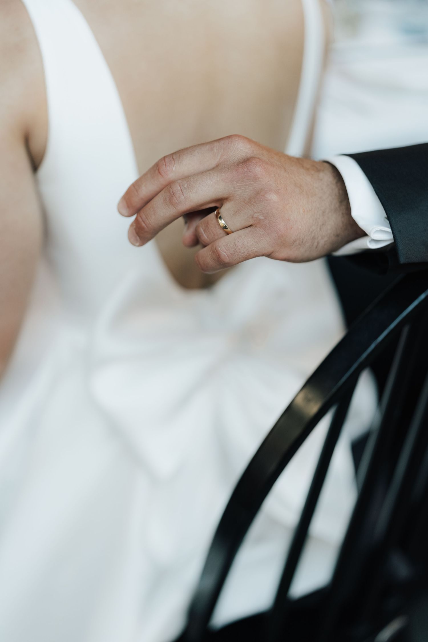 Close-up detail of wedding rings and formal attire during an intimate moment.