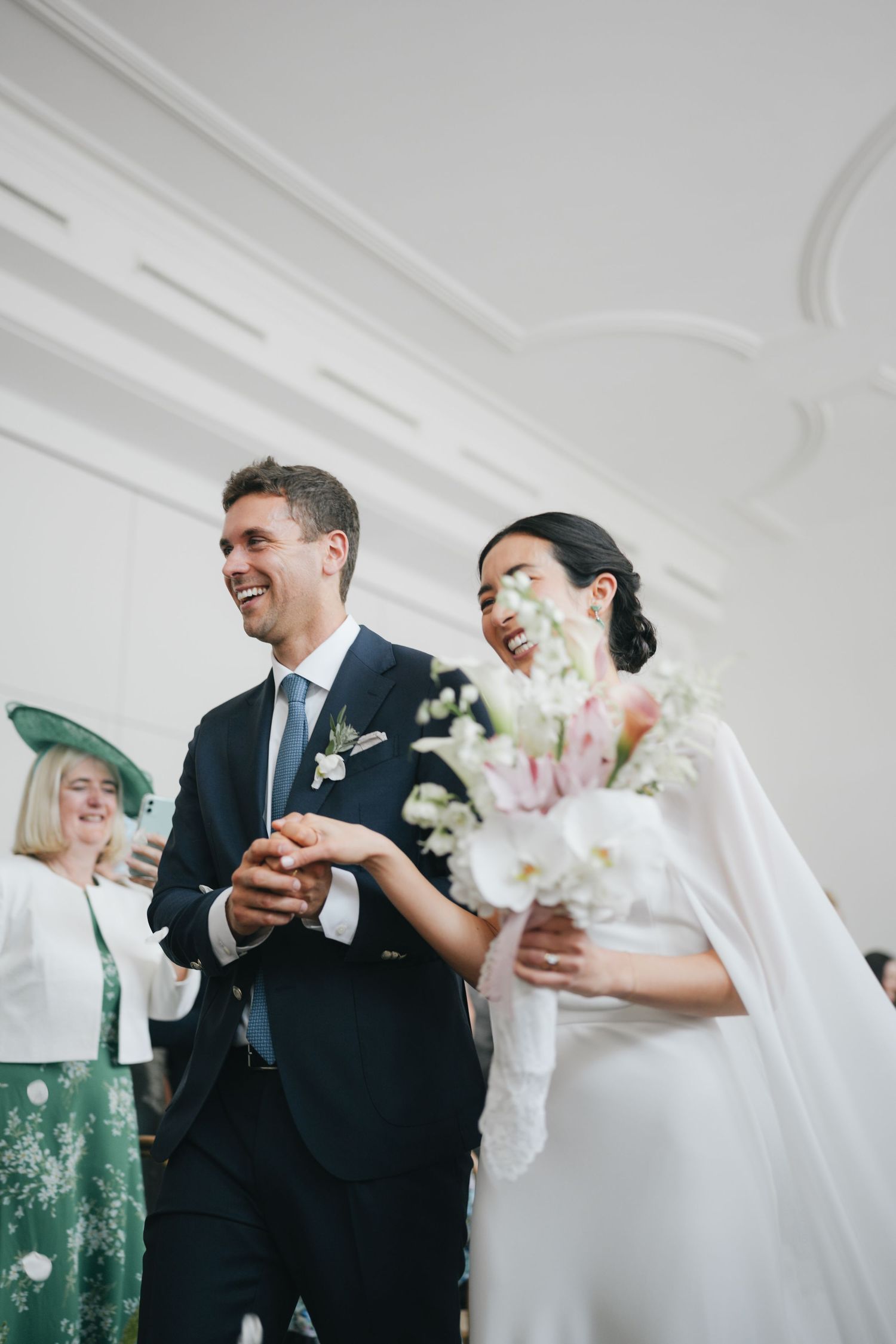Wedding celebration in a bright white interior space with elegant floral arrangements.