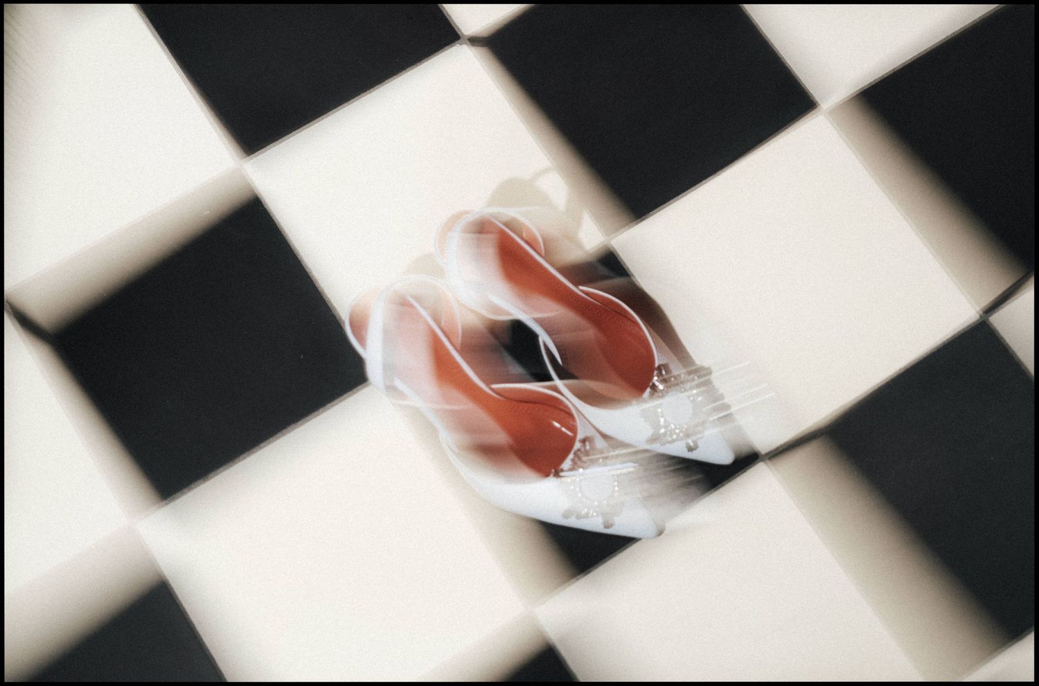 Ballet shoes in soft pink tones displayed on a dramatic checkerboard floor.