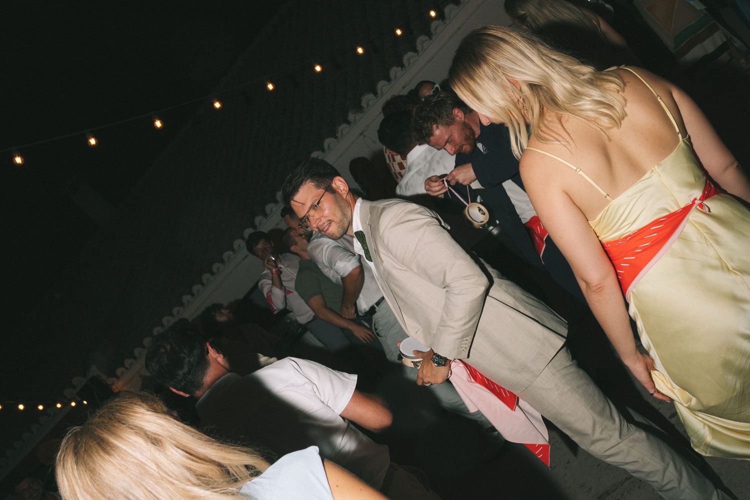 Guests dancing and celebrating on a crowded dance floor at night.