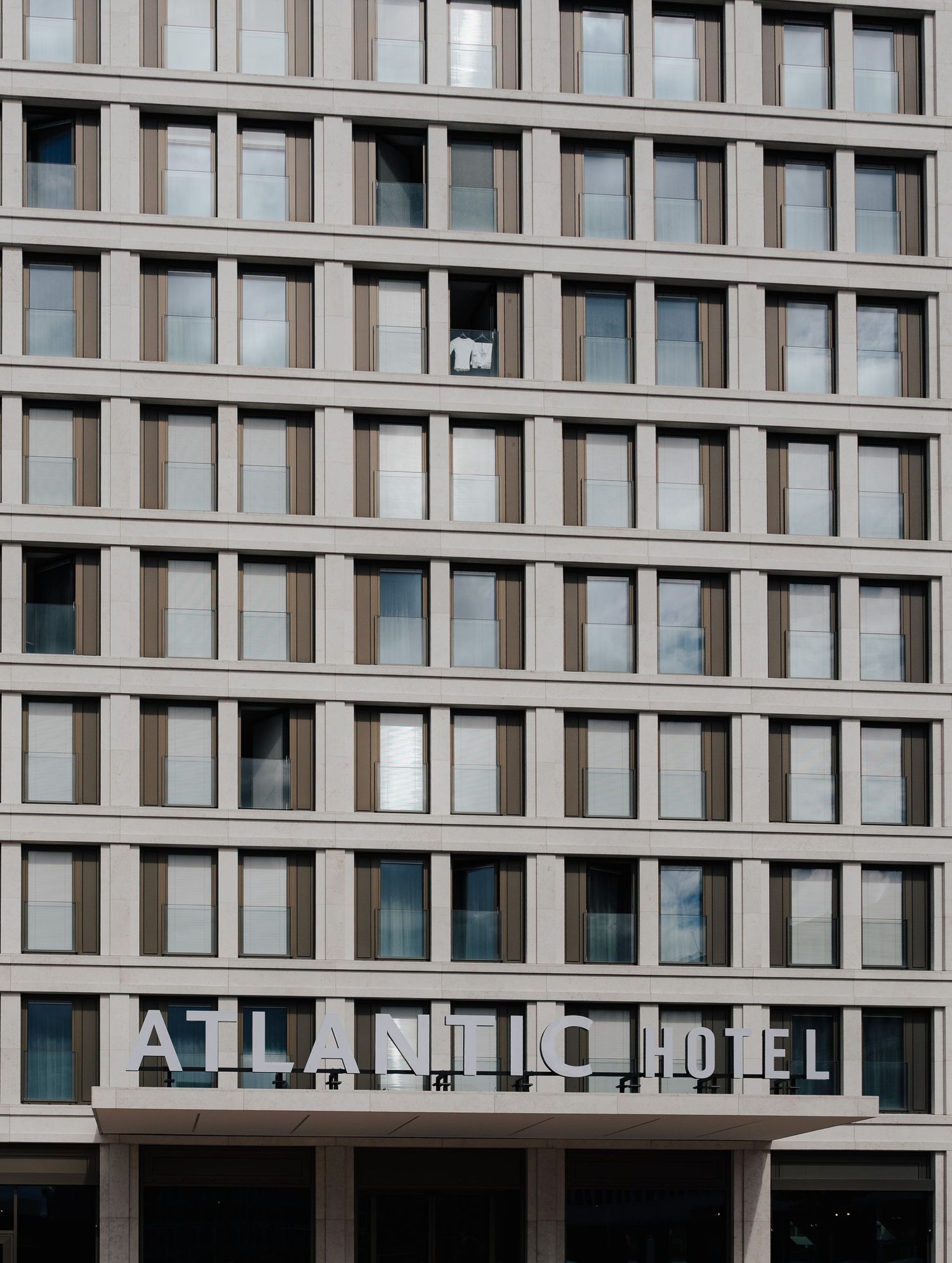 Modern hotel building exterior with repetitive window pattern and architectural details.