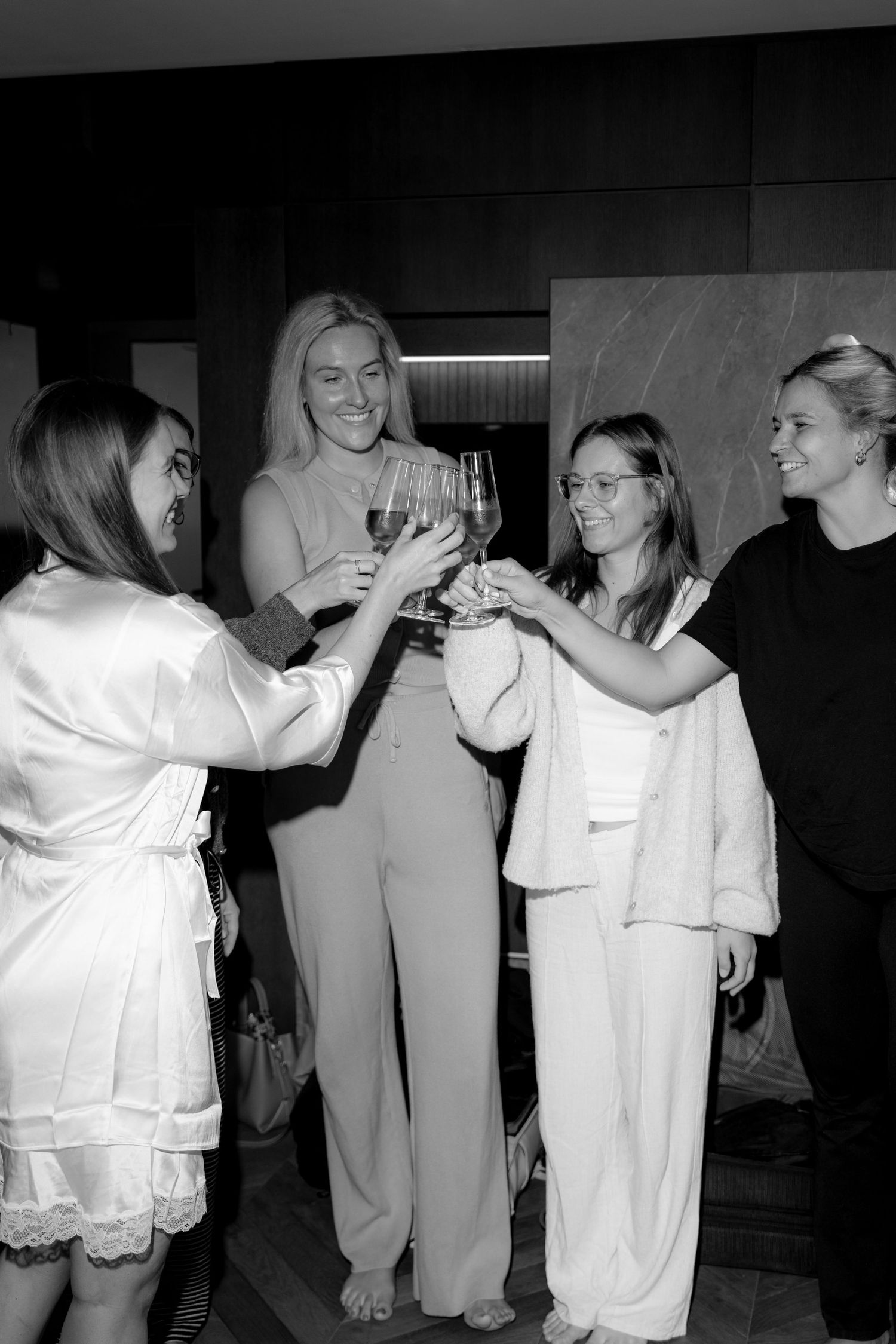 Group wearing white outfits celebrating and dancing together in black and white photo.