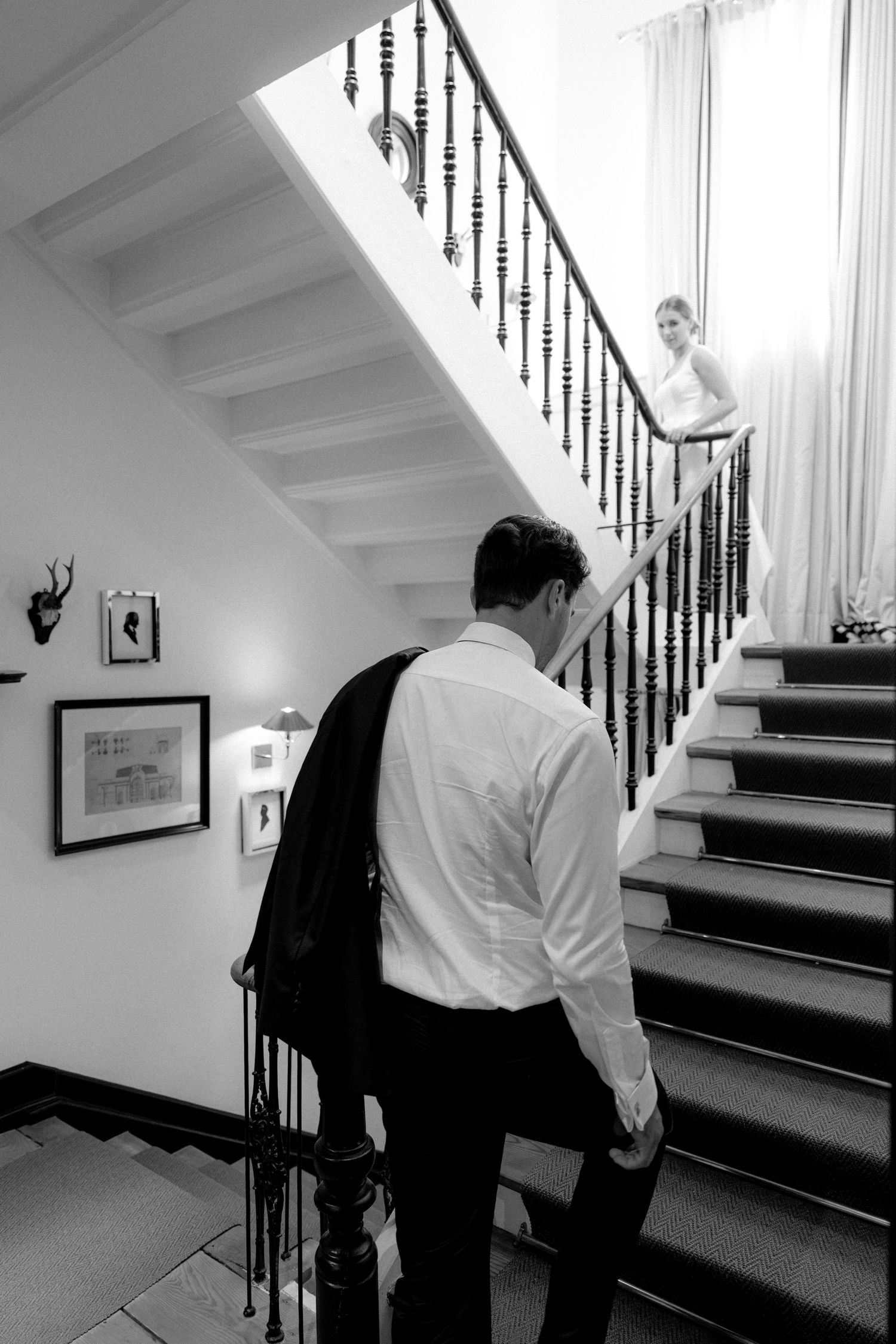 A black and white photo of a couple on a grand staircase with decorative iron railings.