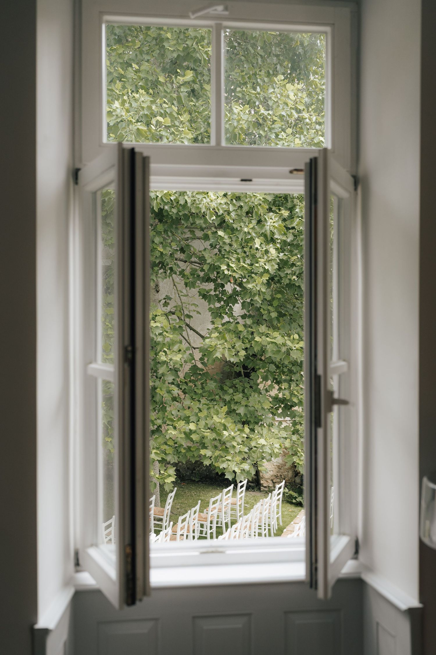 Interior view of white windows overlooking outdoor garden chairs.