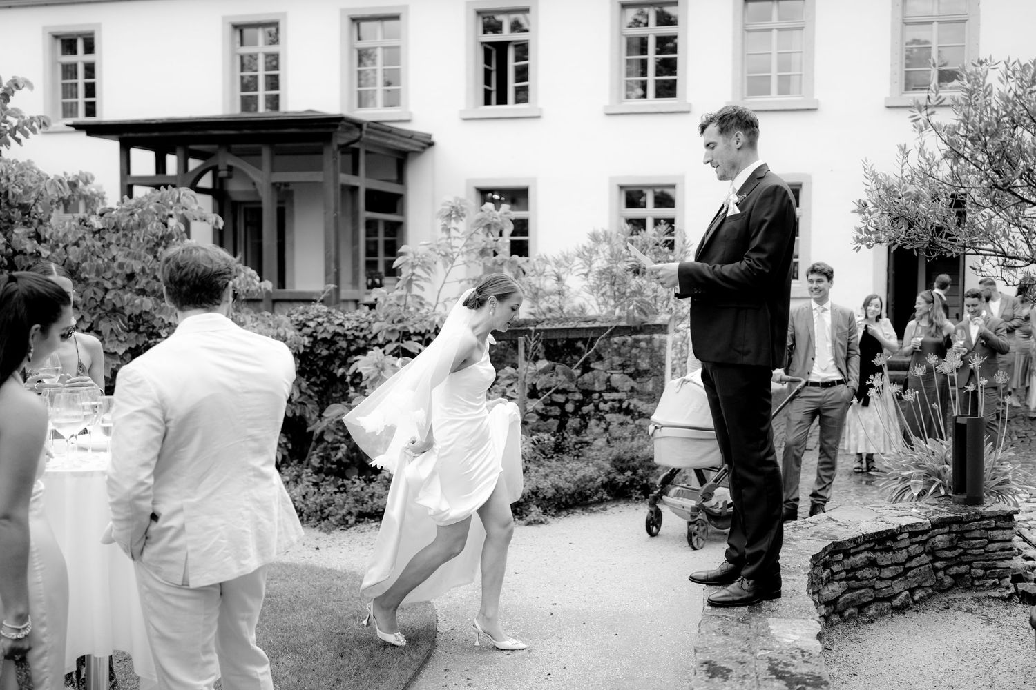 Black and white photo of a wedding celebration outside a historic building.