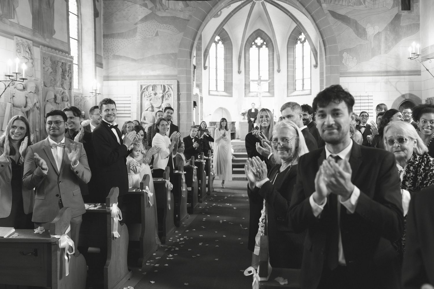 Black and white photograph of people applauding during a church ceremony.