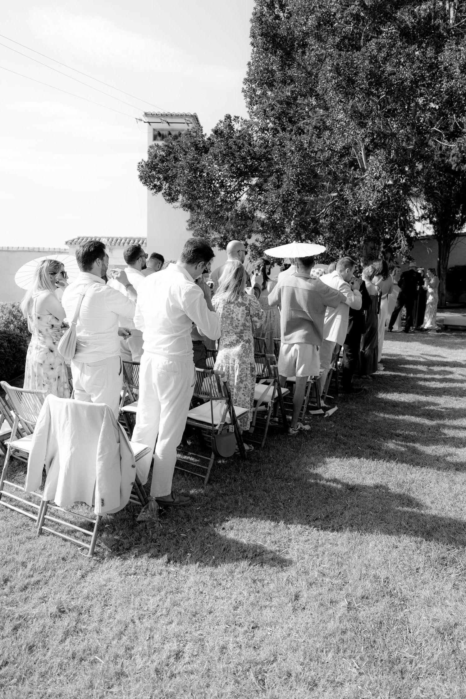 Wedding guests seated outdoors under shady trees for an intimate ceremony.