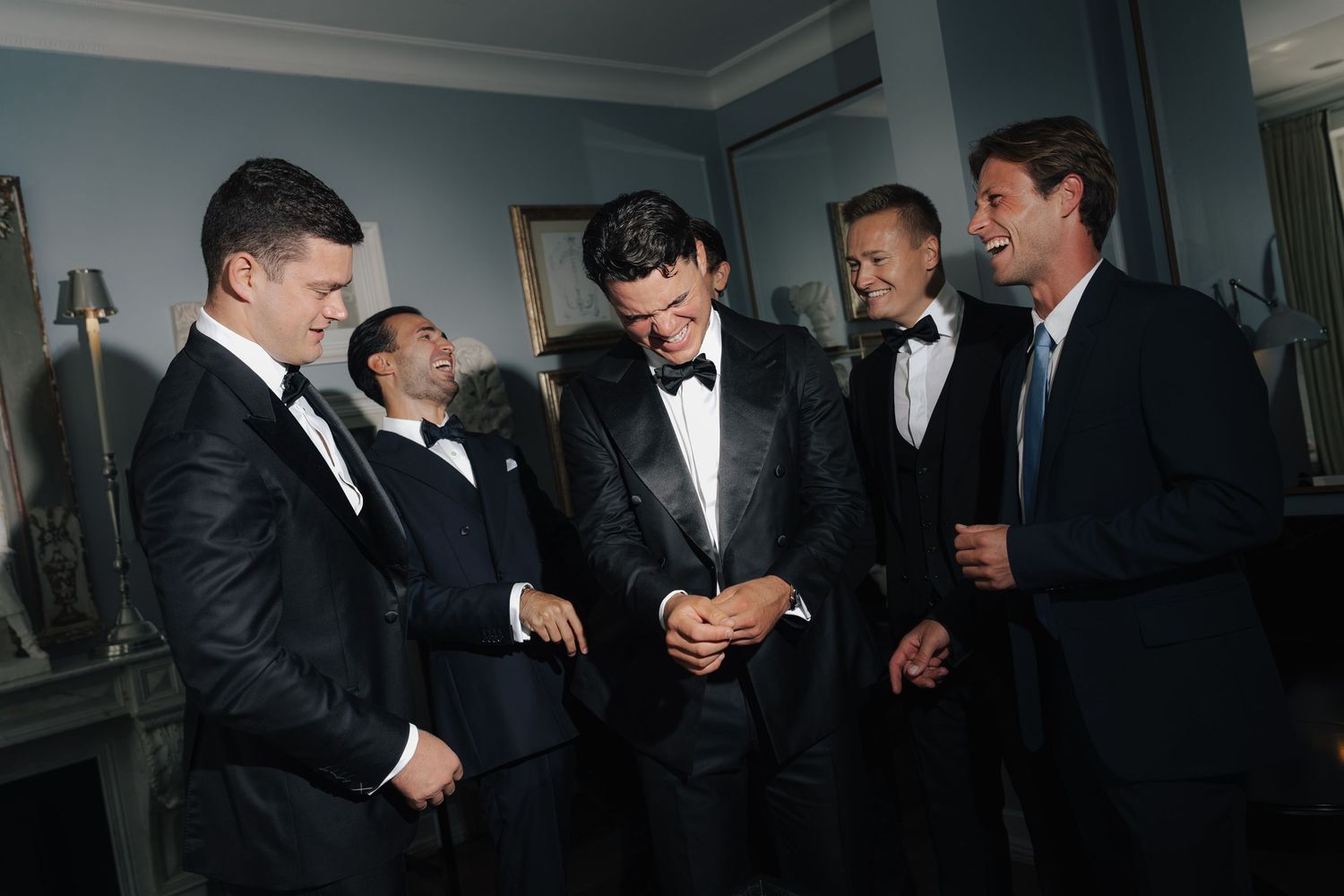 A group of men in formal black tuxedos gathered together in a room.