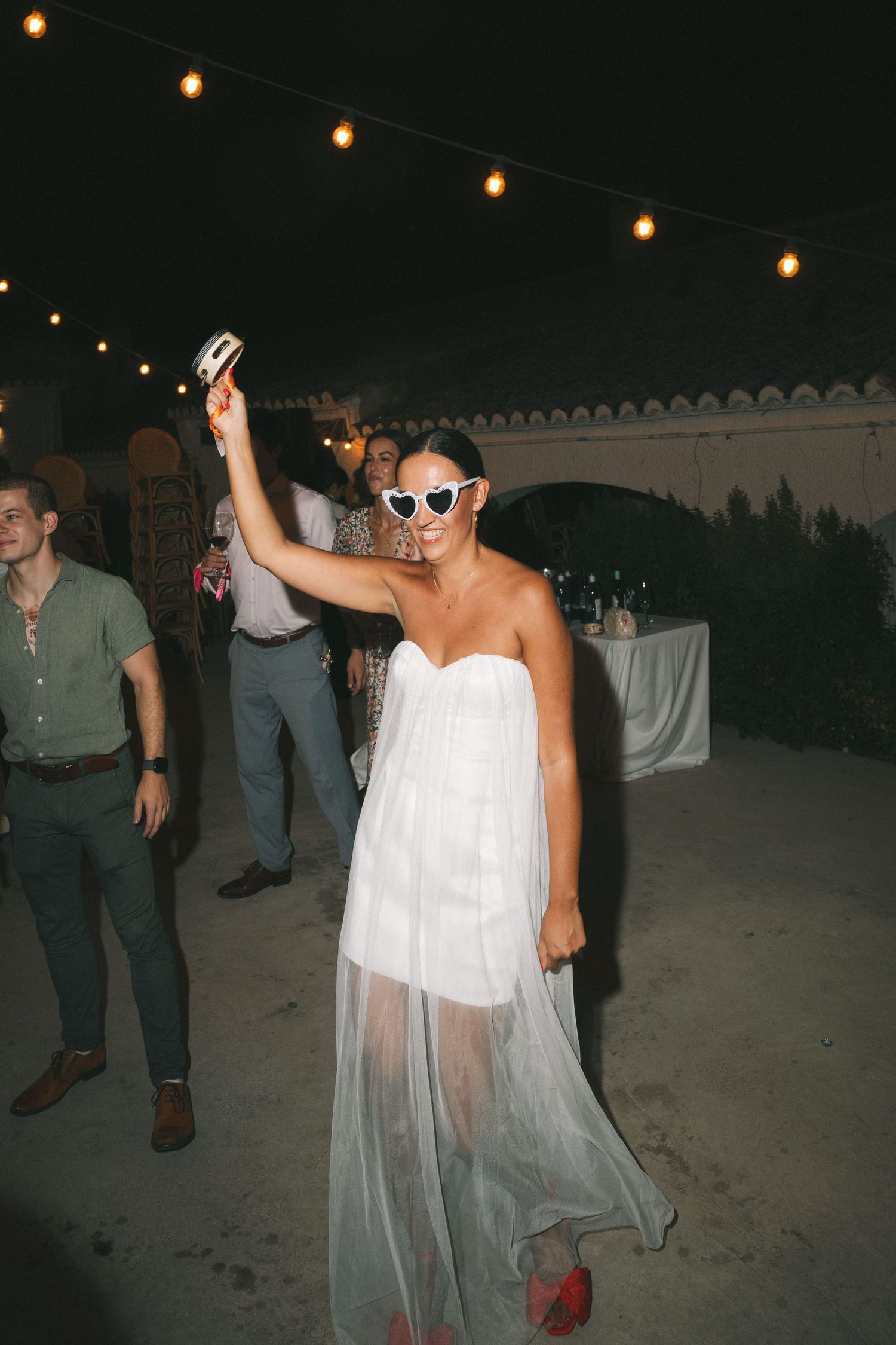 People dancing at a nighttime wedding reception with string lights overhead.