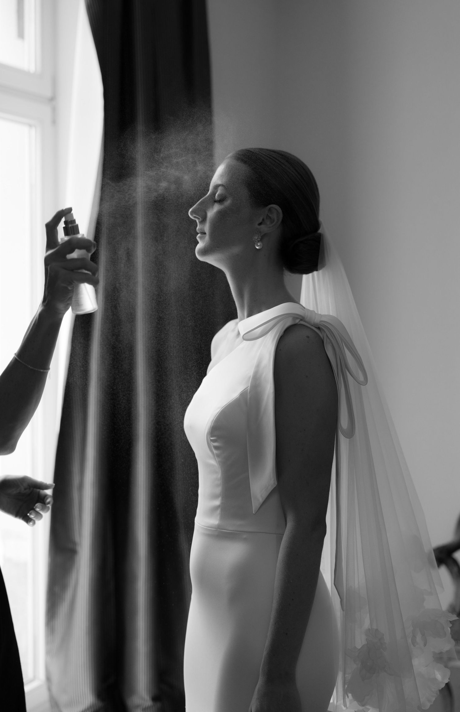 Artistic black and white profile shot of bride getting ready with dramatic window light.
