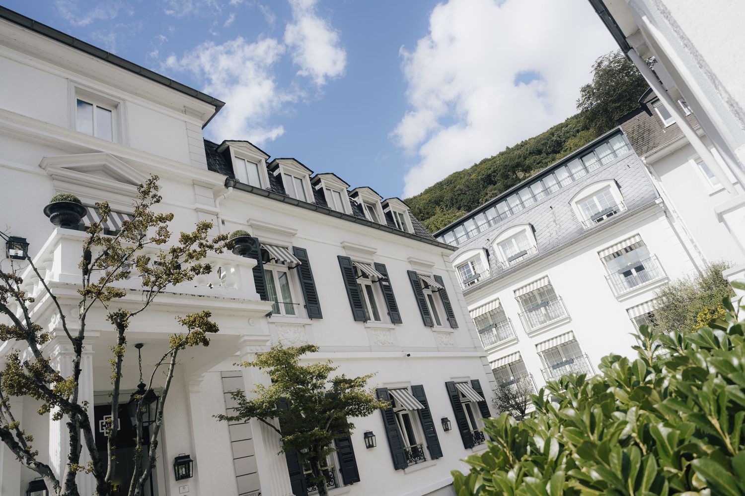 White colonial style mansion exterior with black shutters under blue sky.