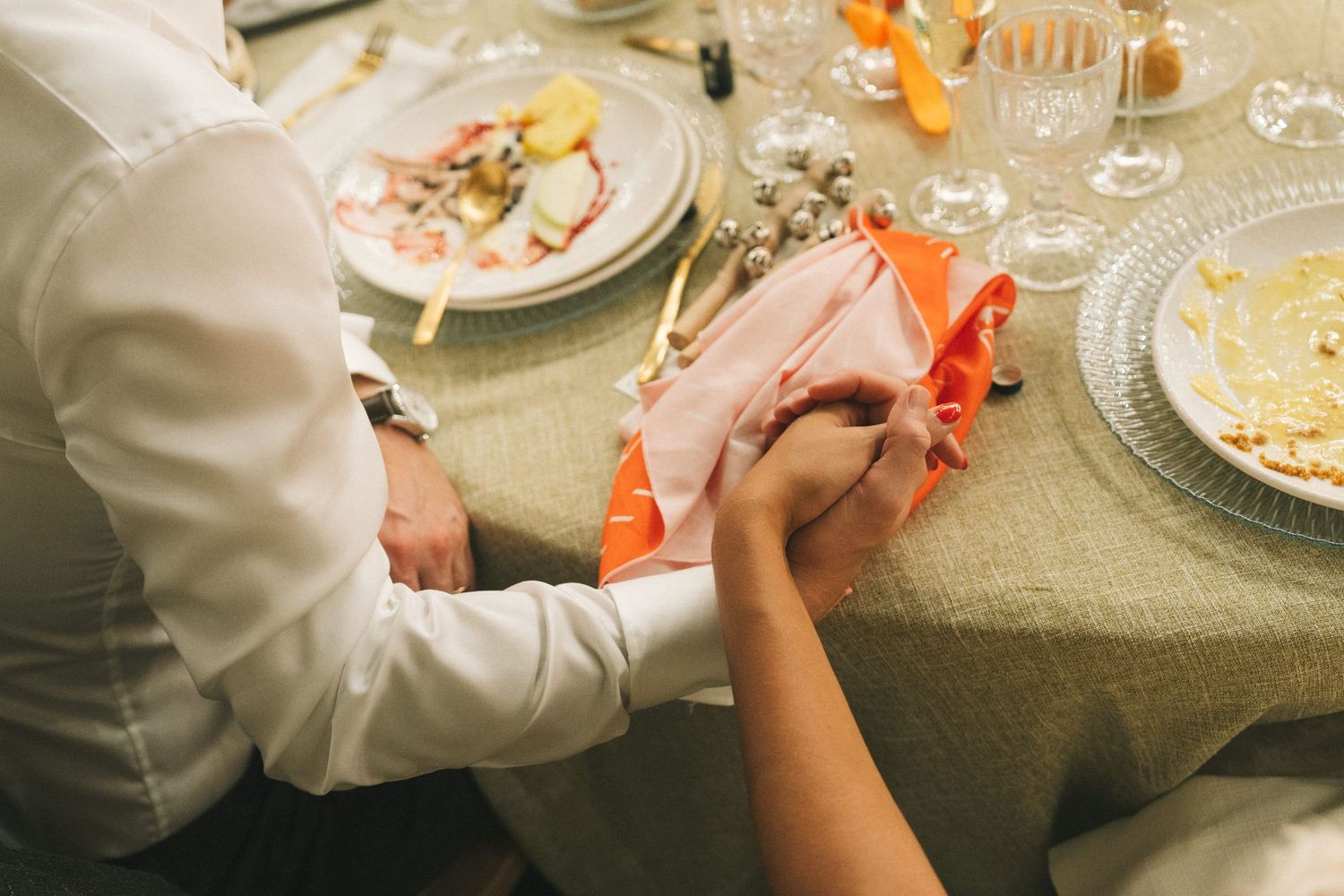 Close-up details of table settings with orange accents at an elegant dinner event.