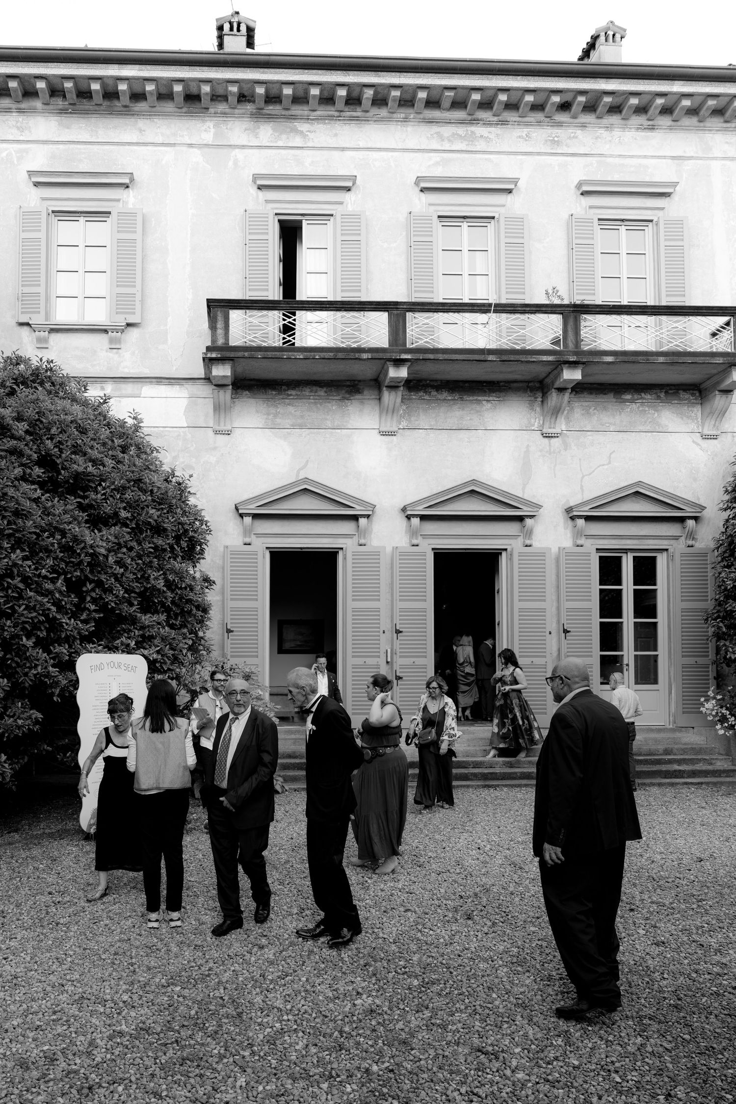 Wedding guests gathered in the courtyard of a historic mansion.