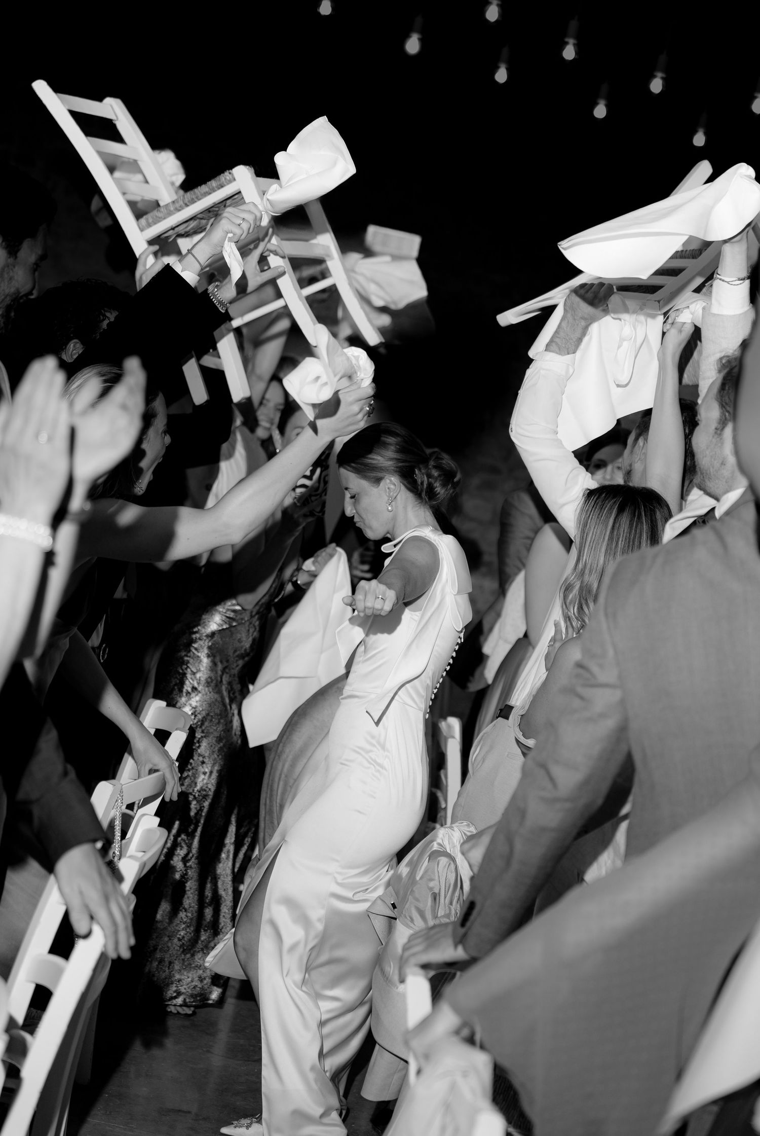 A crowd of celebrants waving white napkins during a festive dance party.