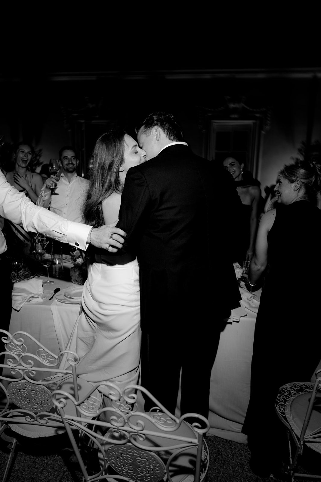 Black and white photo of a bride and groom sharing a kiss on the dance floor at their wedding reception.
