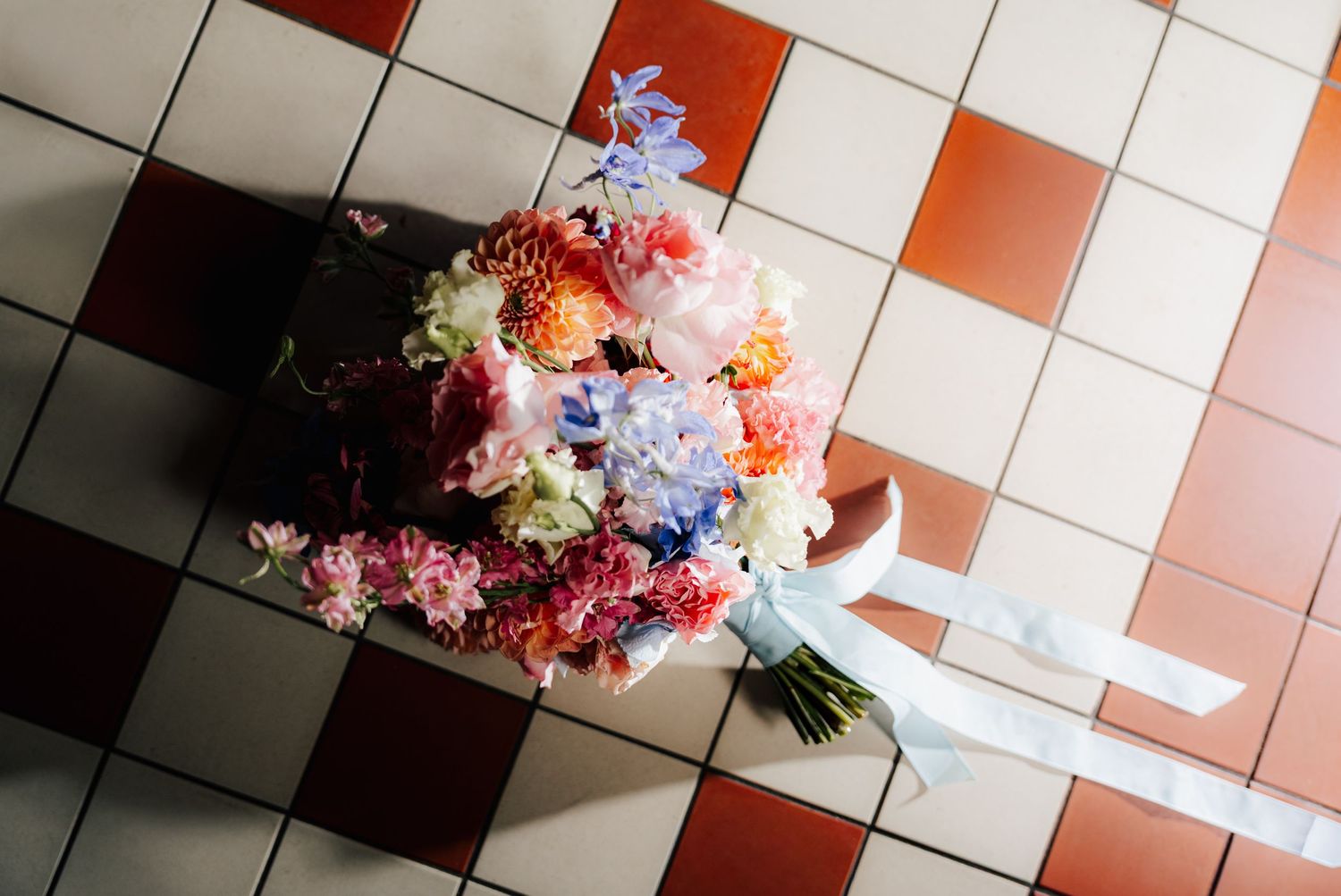 Overhead view of colorful floral arrangements on checkered tile floor.