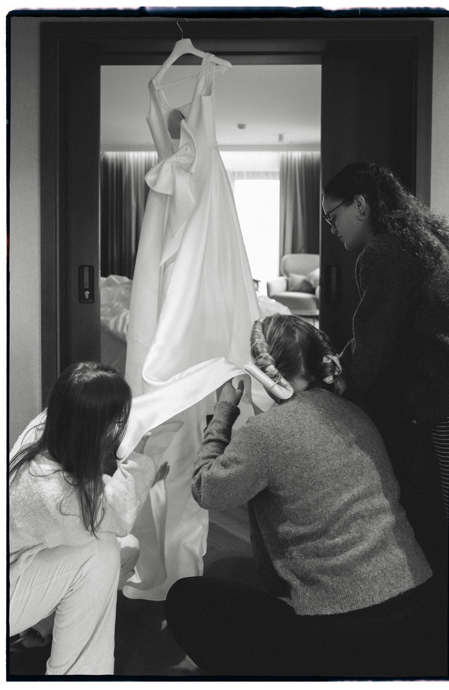 Black and white photos showing someone holding up a white dress or garment.
