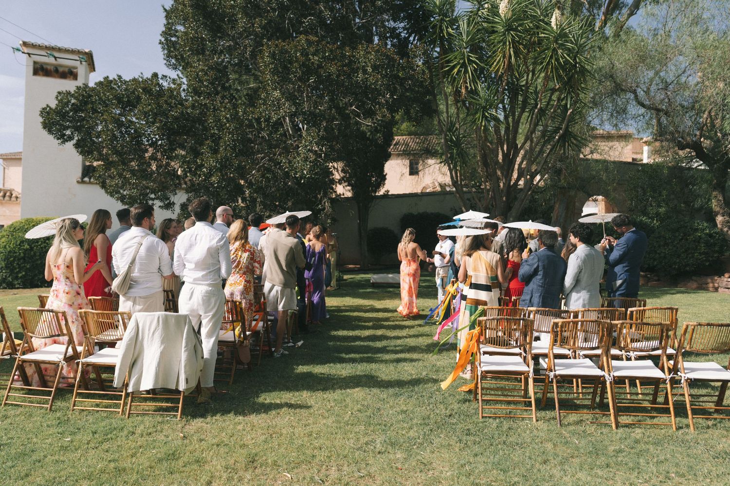 Outdoor wedding ceremony setup with wooden chairs arranged on a grassy lawn.