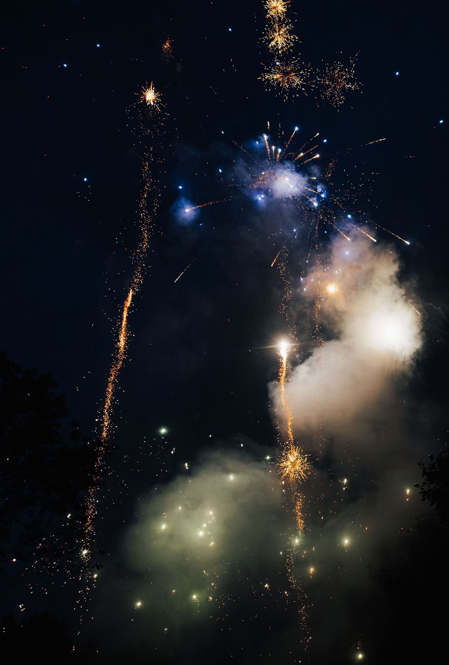 Colorful fireworks display lighting up night sky with blue and white bursts.