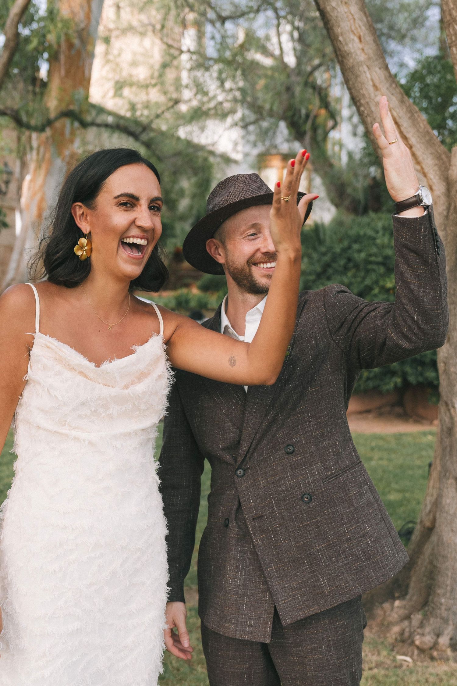A couple celebrates joyfully outdoors wearing formal attire.