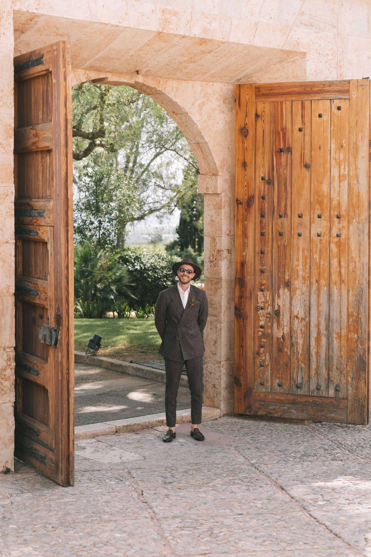 Series showing figures emerging through rustic wooden doorways in a stone archway.