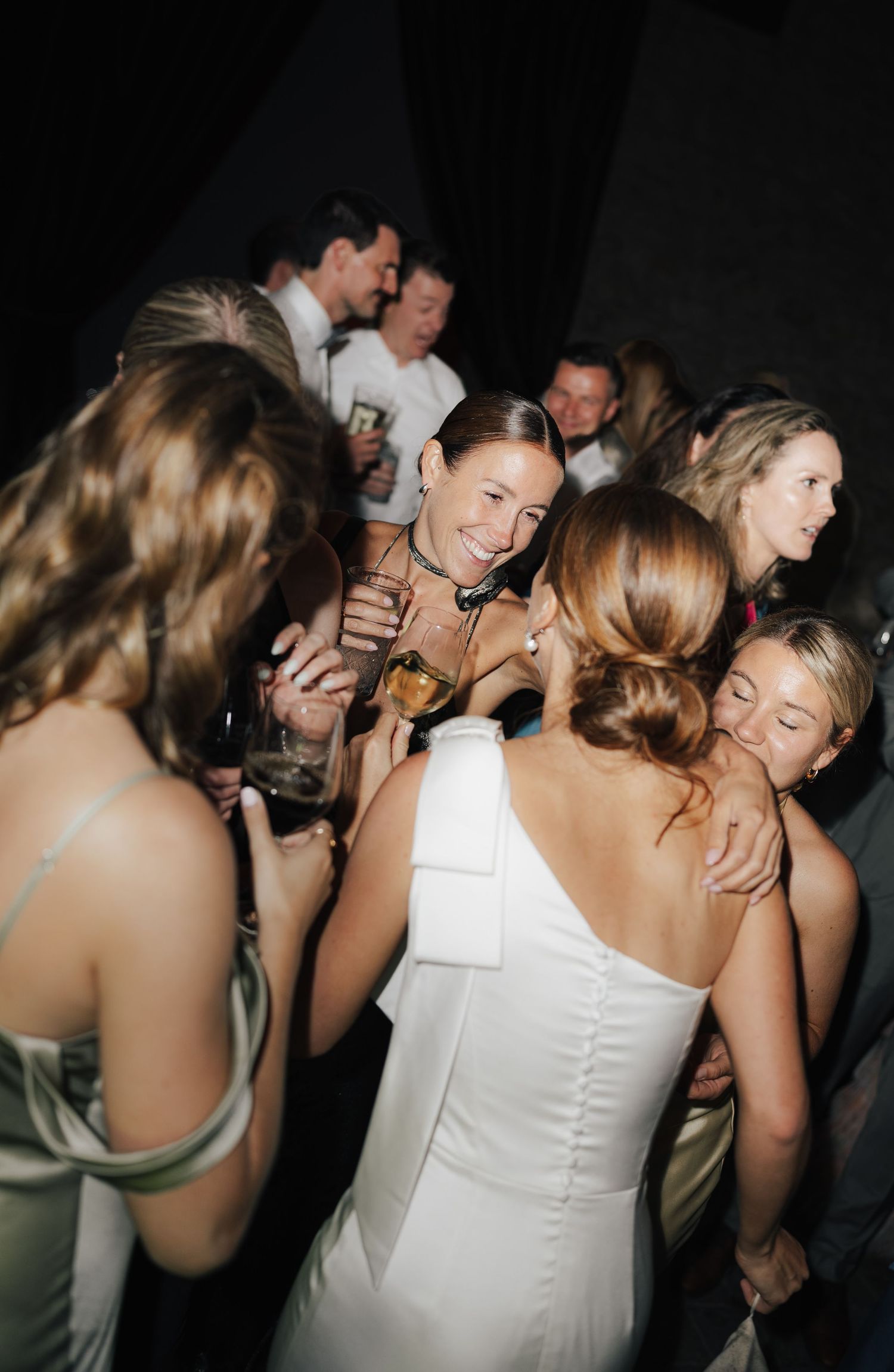 Group of party guests dancing and celebrating in formal wear.