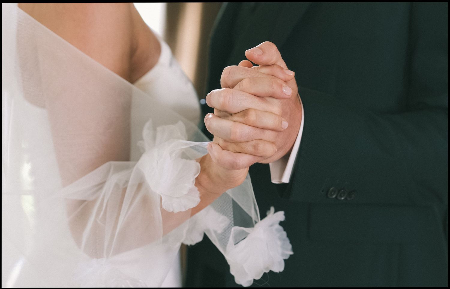 Close-up of formal dance partners holding hands in elegant attire.
