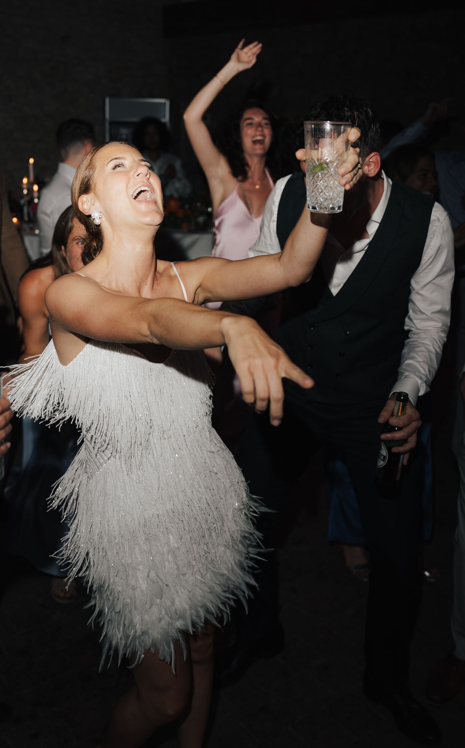 Person in white fringe dress dancing energetically at a party.
