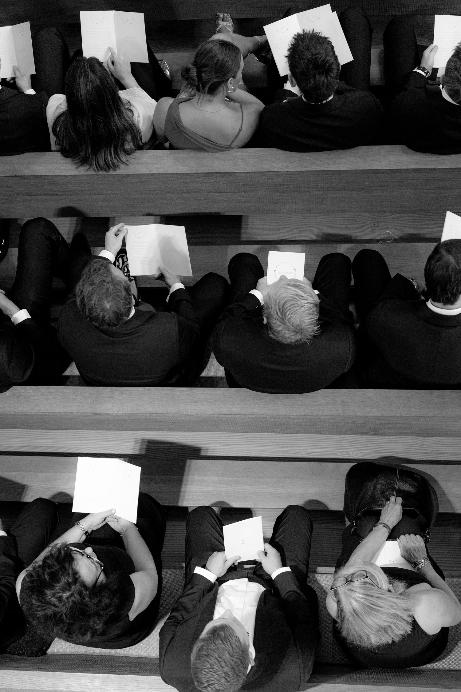 Overhead view of wedding guests seated in rows of wooden church pews.