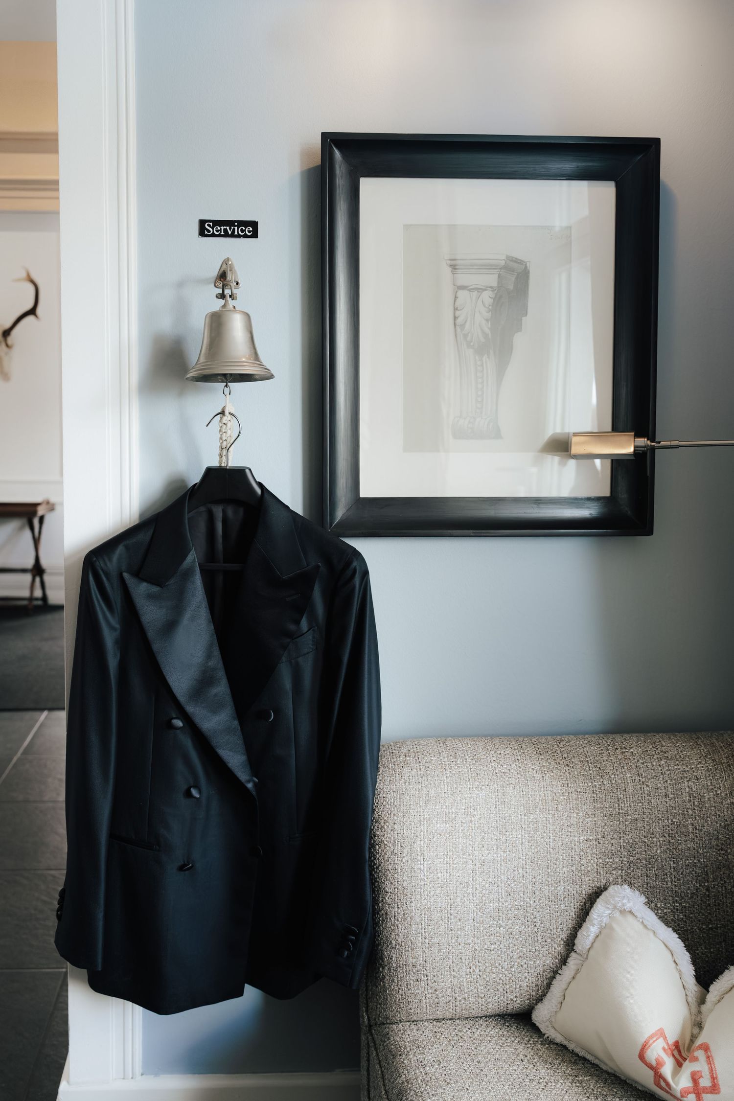 Black tuxedo jackets hanging on display in an elegant room with framed artwork.