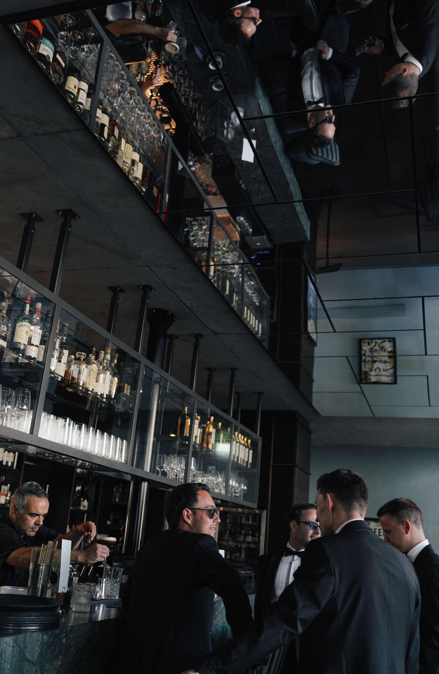 A dimly lit bar interior with well-stocked shelves and pendant lighting.