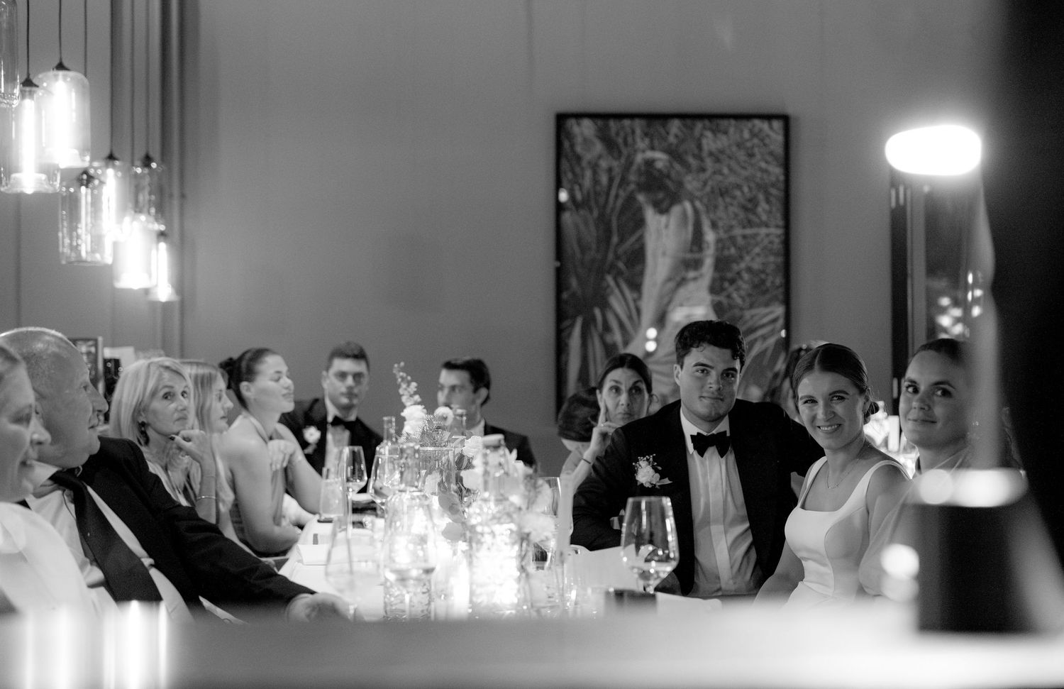 Black and white photo of wedding reception guests dining at an elegant table setting.