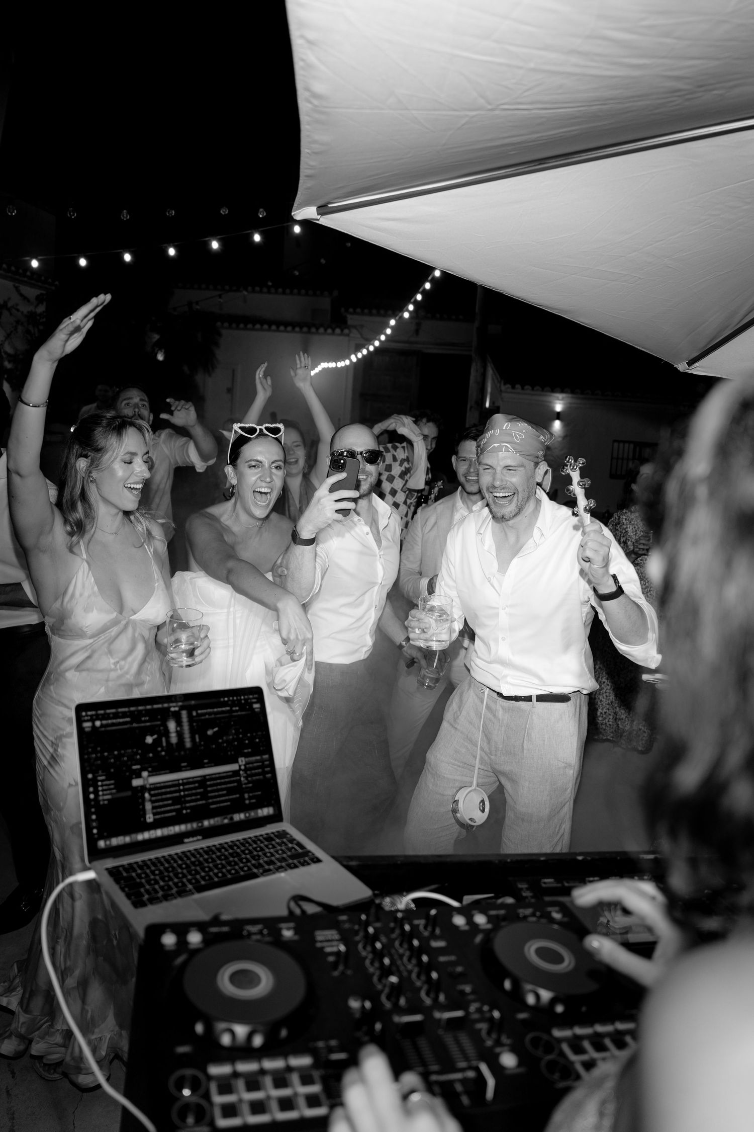 DJ booth at a lively wedding reception with guests dancing and celebrating.