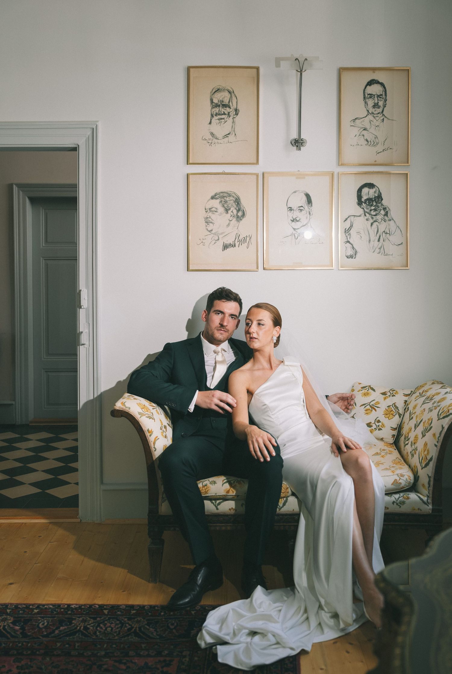Elegant interior room with vintage portrait sketches and wedding couple on antique furniture.