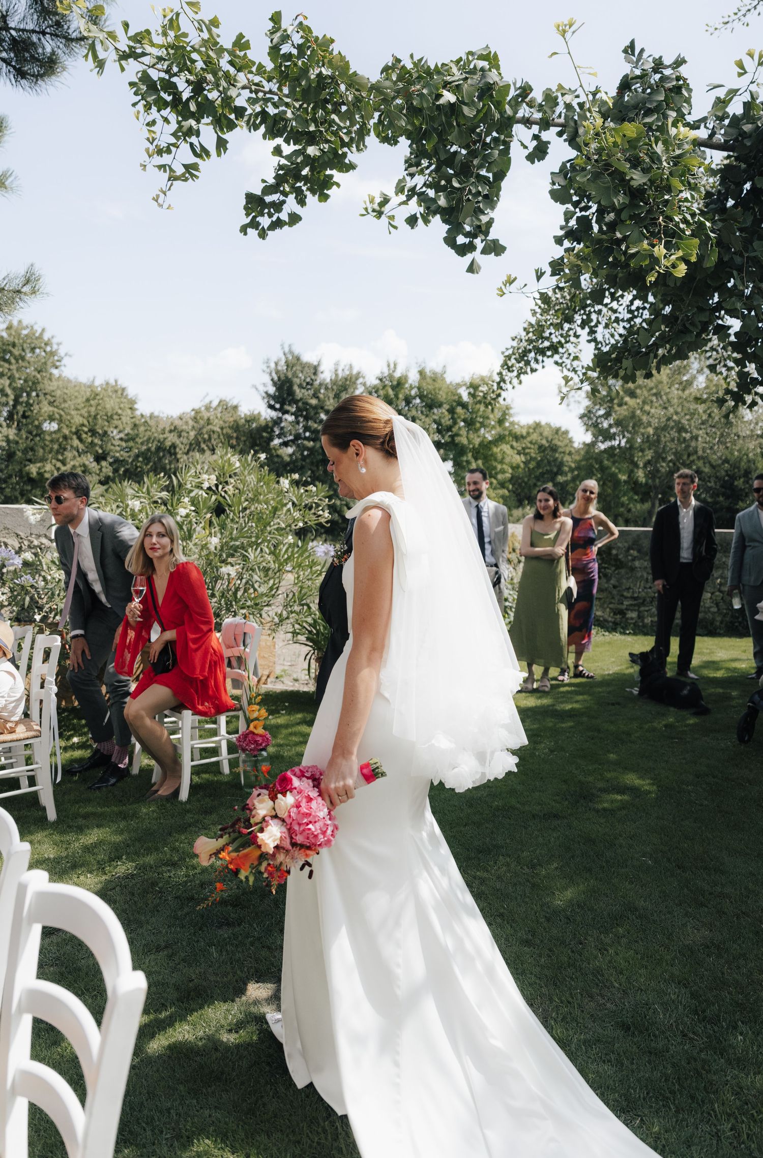 Outdoor garden wedding ceremony setup with white chairs and floral arrangements.