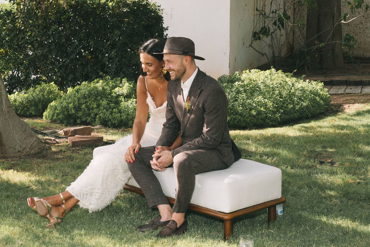 A couple relaxes on outdoor furniture in a garden setting during a sunny afternoon.
