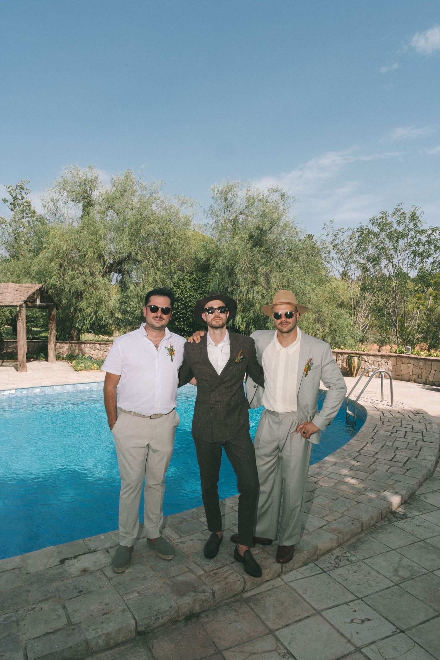 Group standing by a bright blue swimming pool at an outdoor venue.