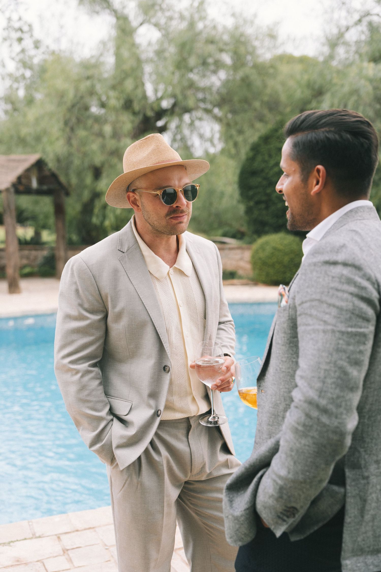 Two guests having conversation by swimming pool at elegant outdoor event.