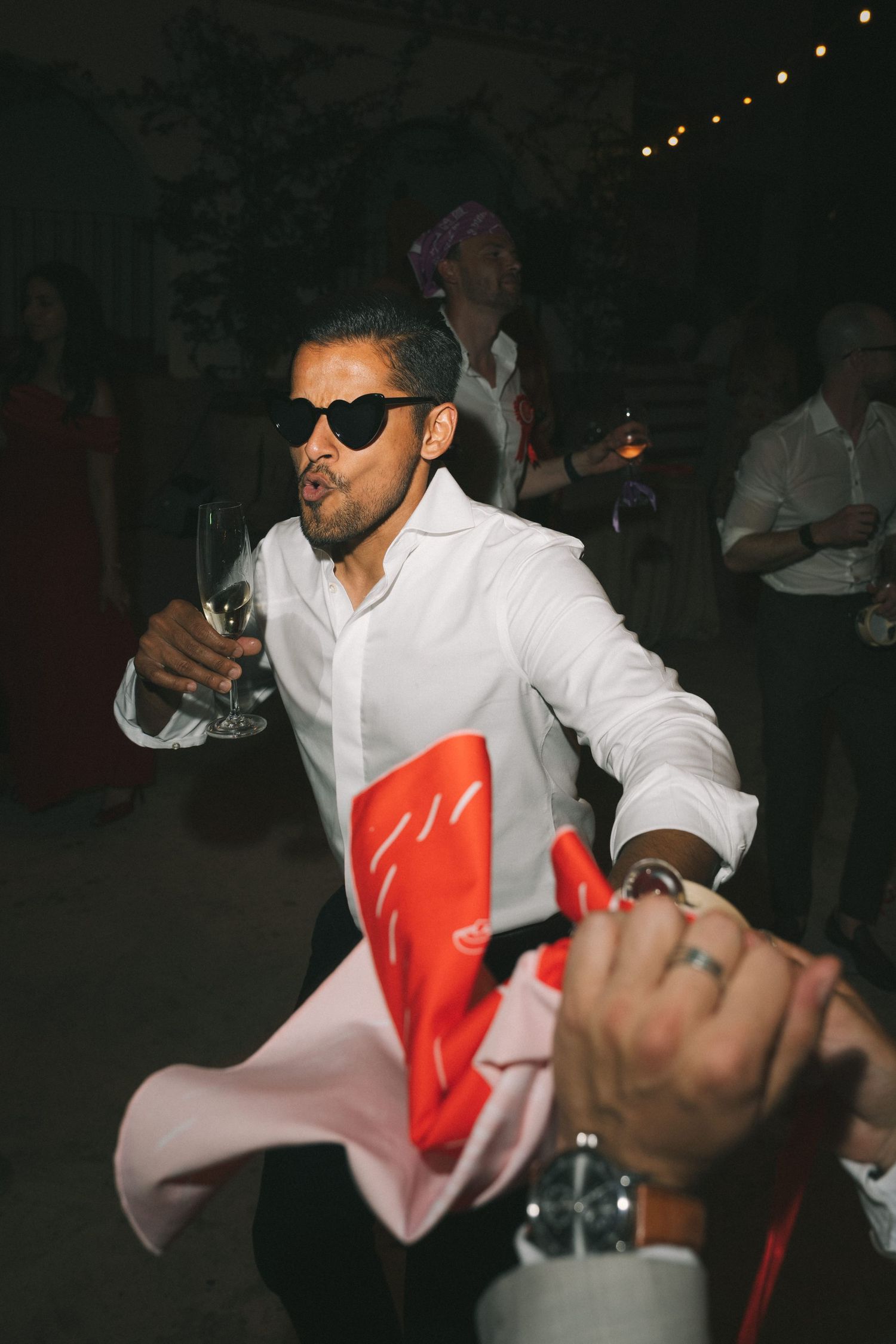 Energetic dance moves at a wedding reception with someone in white and red attire.