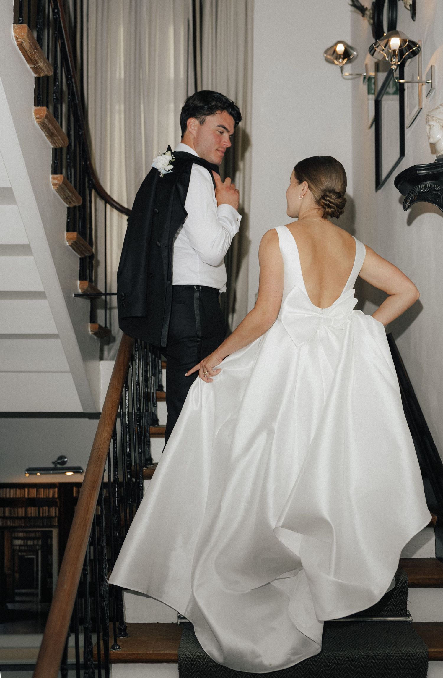A bride in a flowing white gown descends an elegant spiral staircase.