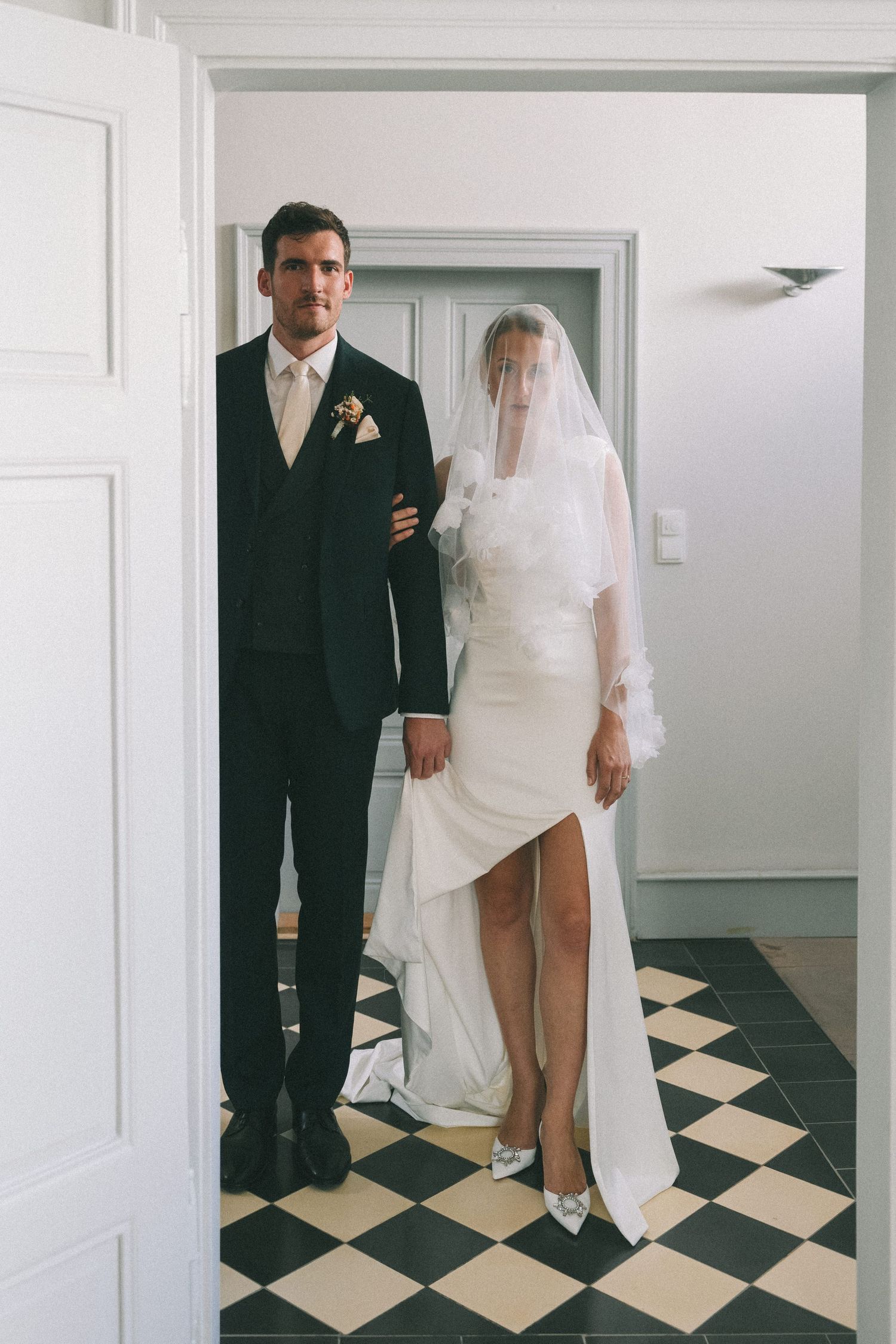 Wedding couple poses on black and white checkered floor in modern interior.