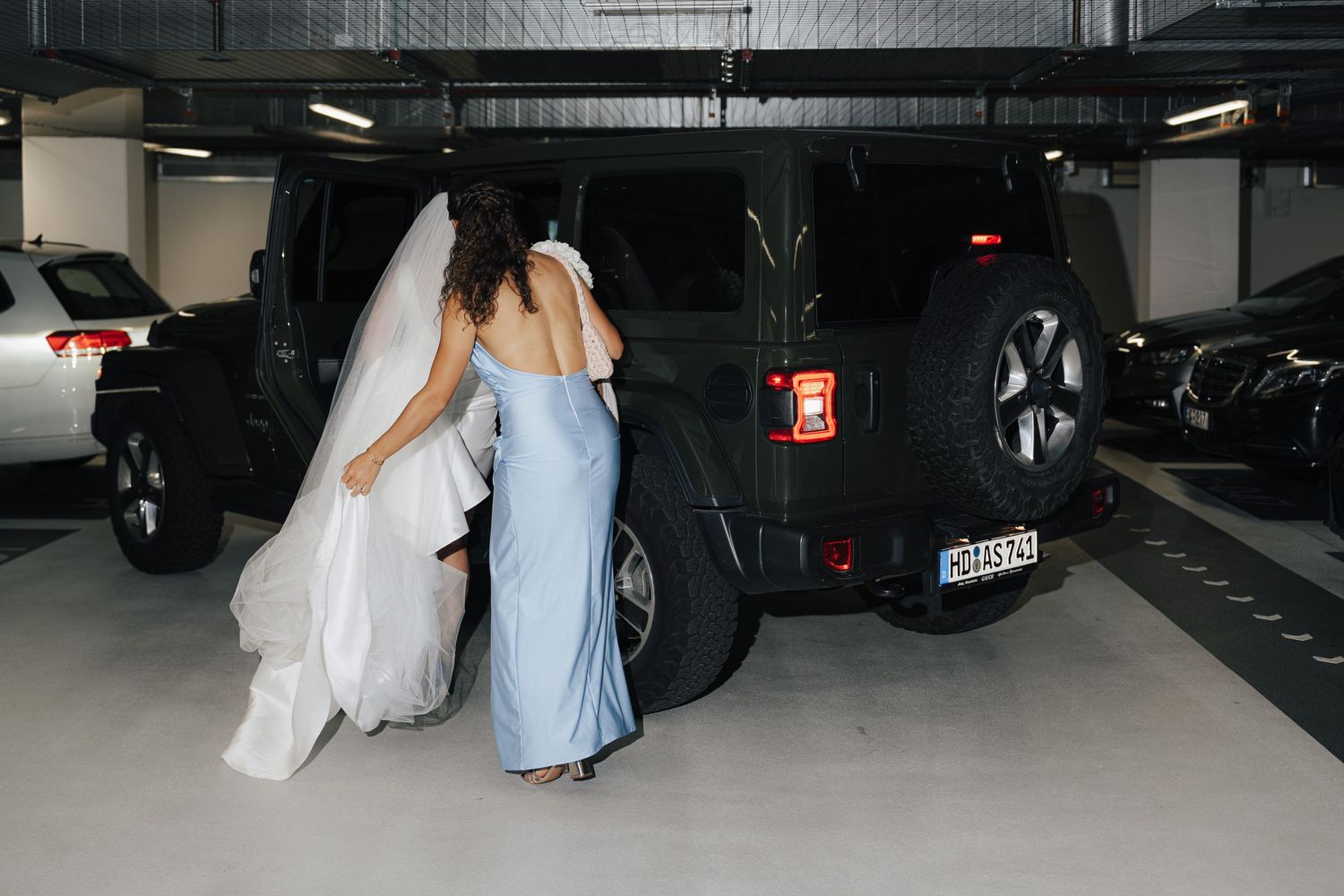 People walking through parking garage in formal attire.