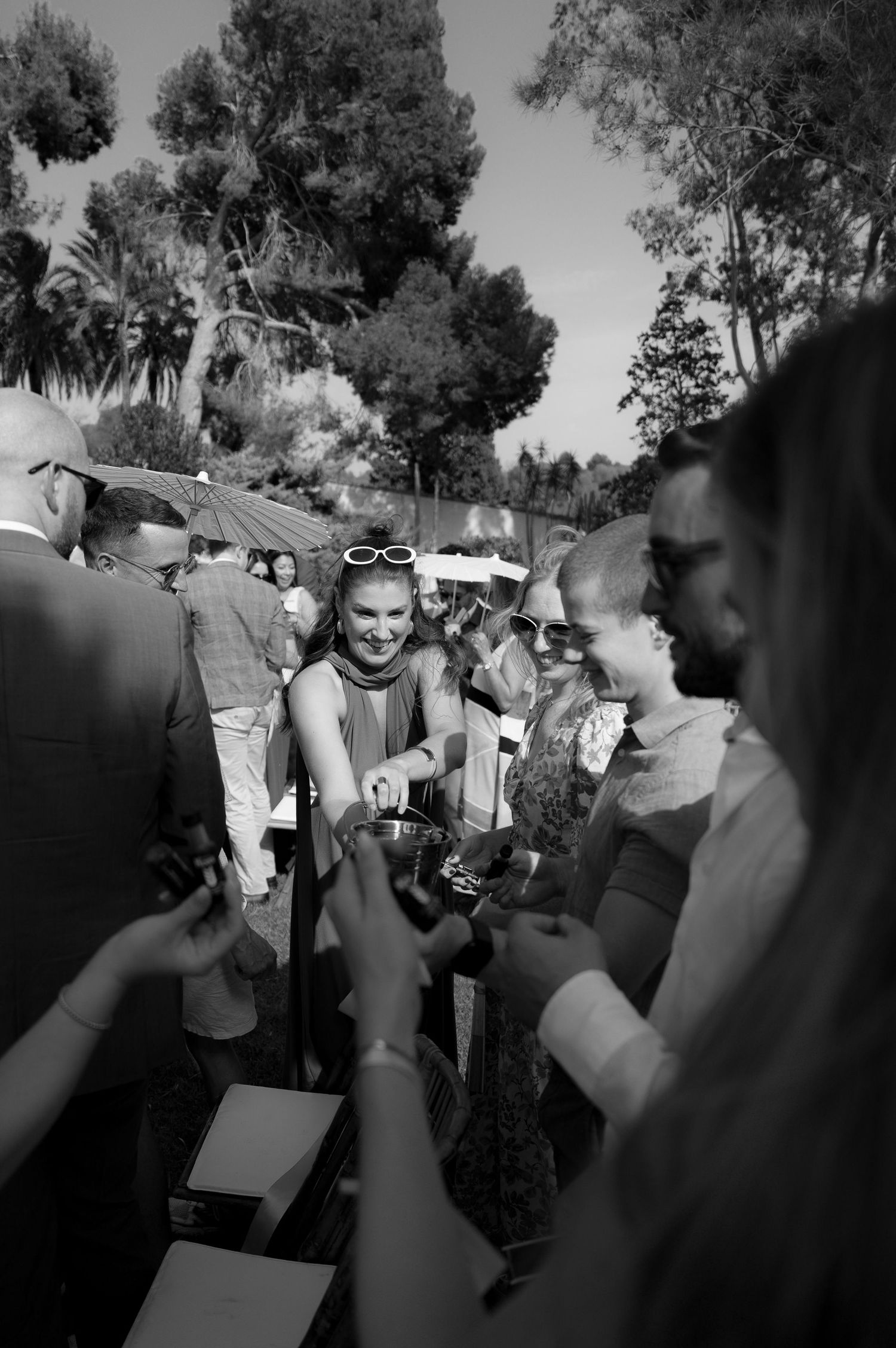 Black and white photo of guests mingling at an outdoor celebration.