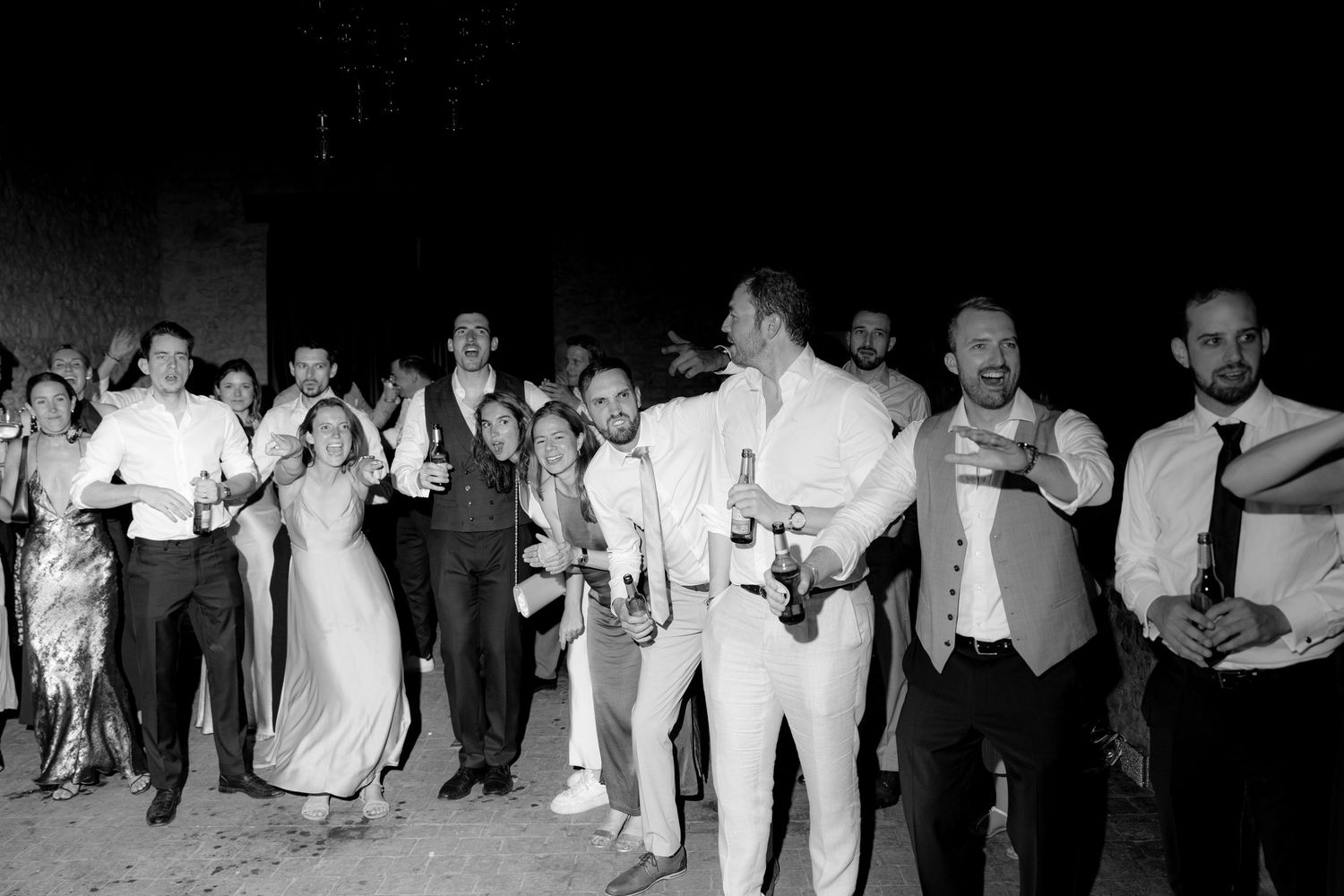 Large group of party guests dancing in black and white photography.
