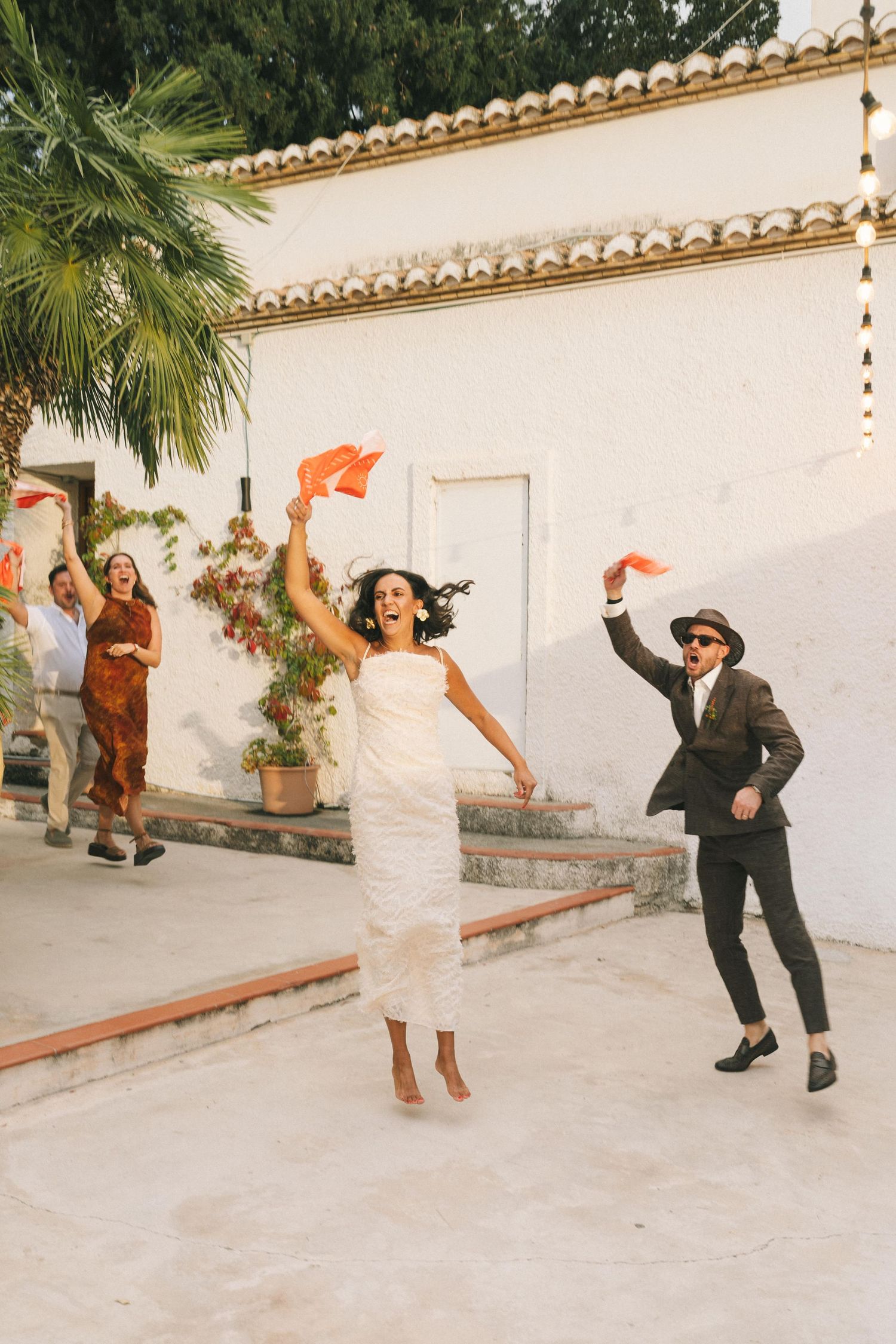Wedding party dancing and celebrating in front of a white Spanish colonial building.