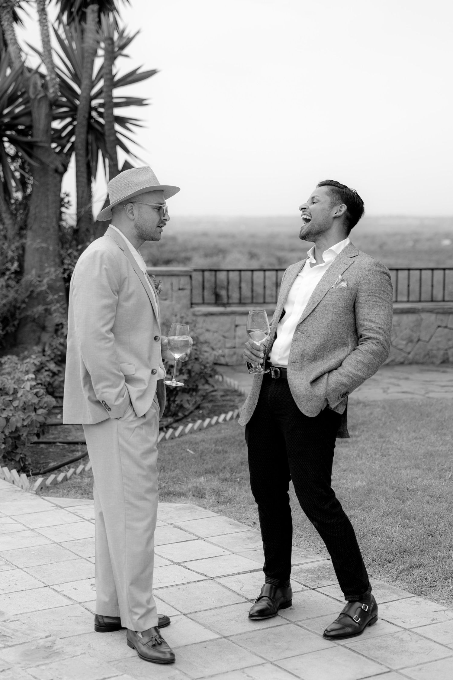 Black and white photos of two people sharing a lighthearted moment on a terrace with palm trees.
