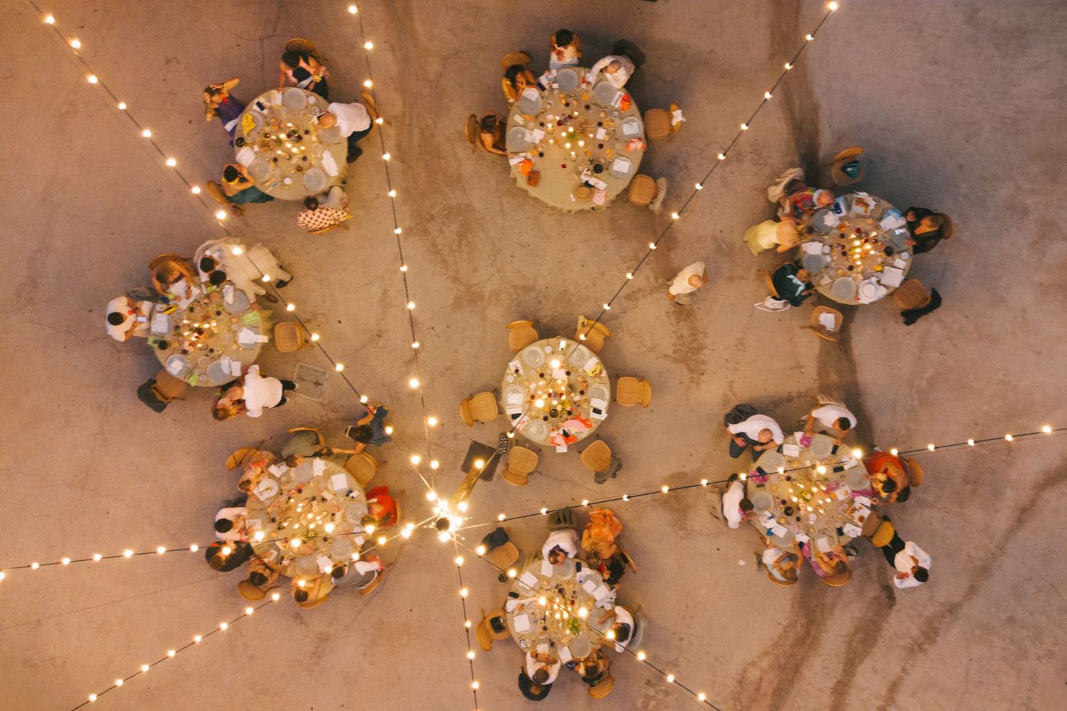 Overhead view of wedding reception tables with string lights and guests dining.
