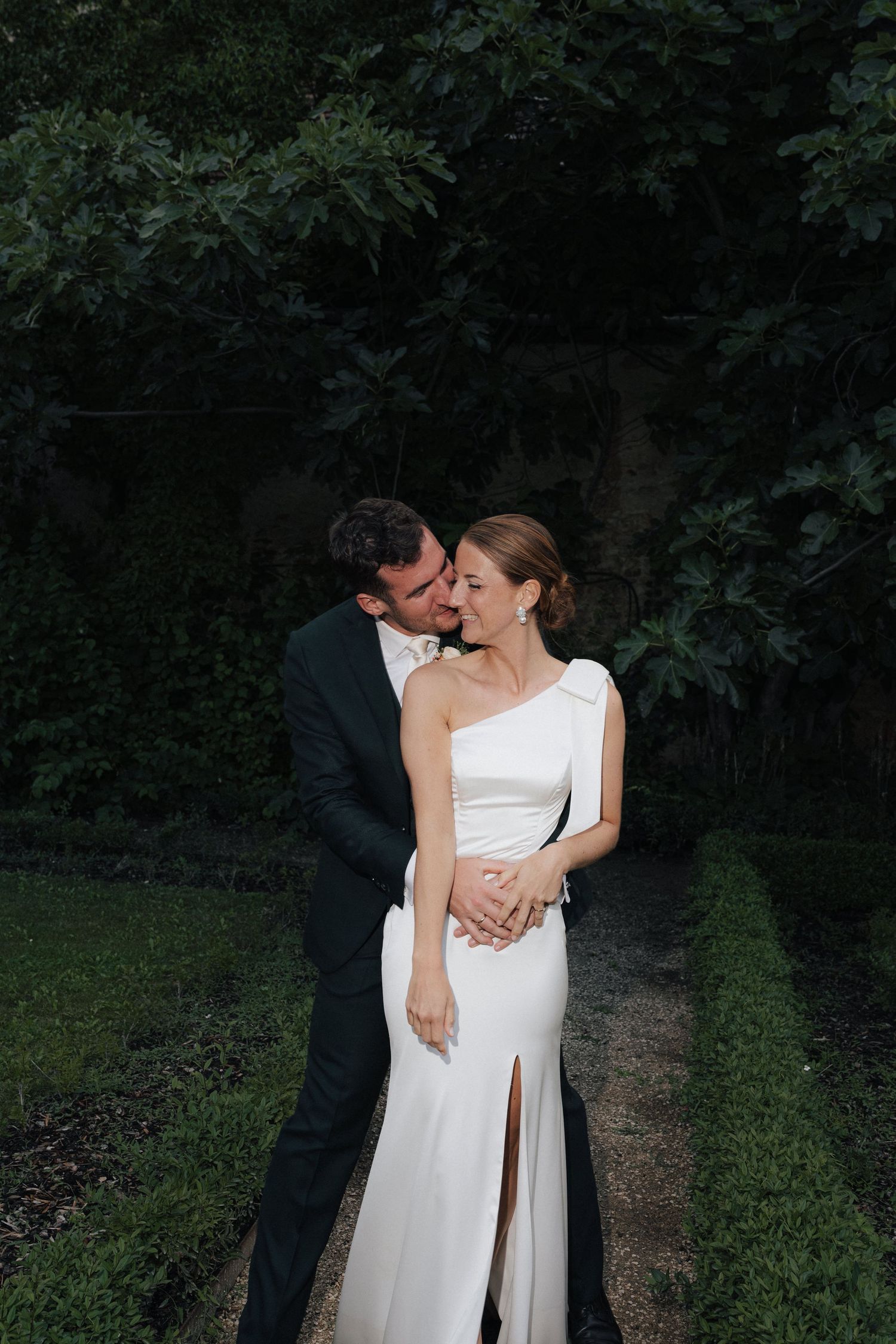 An intimate moment captured in a garden setting with formal attire.